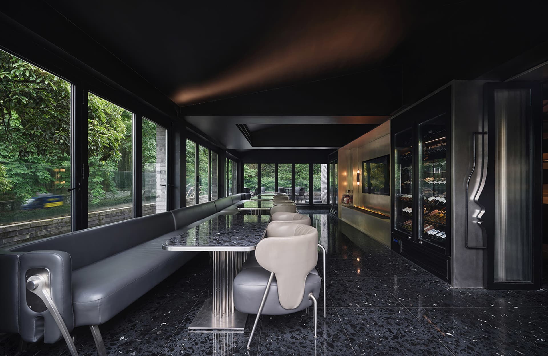 A modern restaurant interior with a large glass dining table surrounded by multiple chairs in a sophisticated and inviting atmosphere