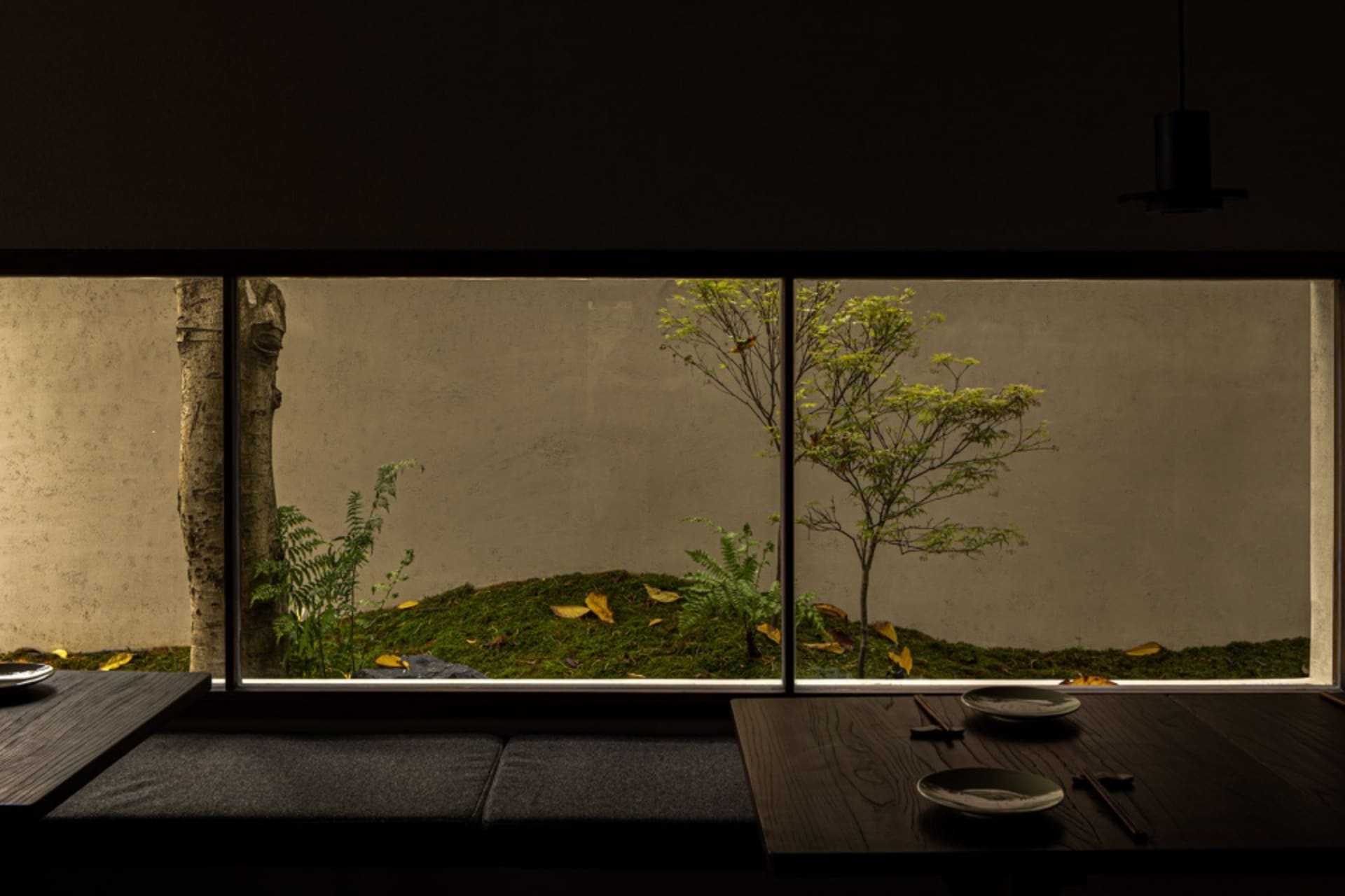 Cozy dining space with a cushioned bench, two dining tables, and three chairs, set in a warm and inviting atmosphere