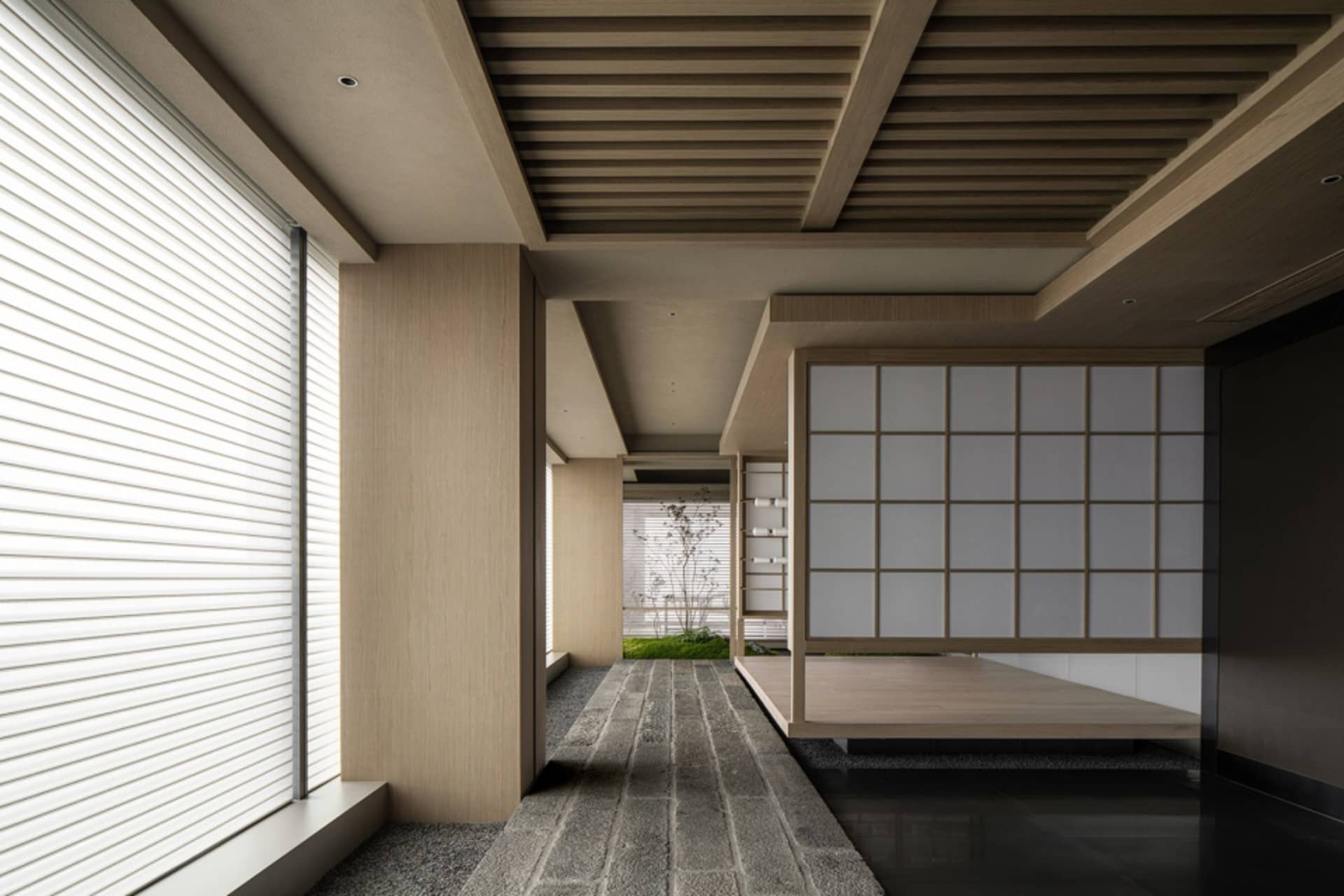 亞洲風格客廳區域，木質地板與牆面，一室設有床鋪，另一室置有餐桌，營造寧靜舒適氛圍