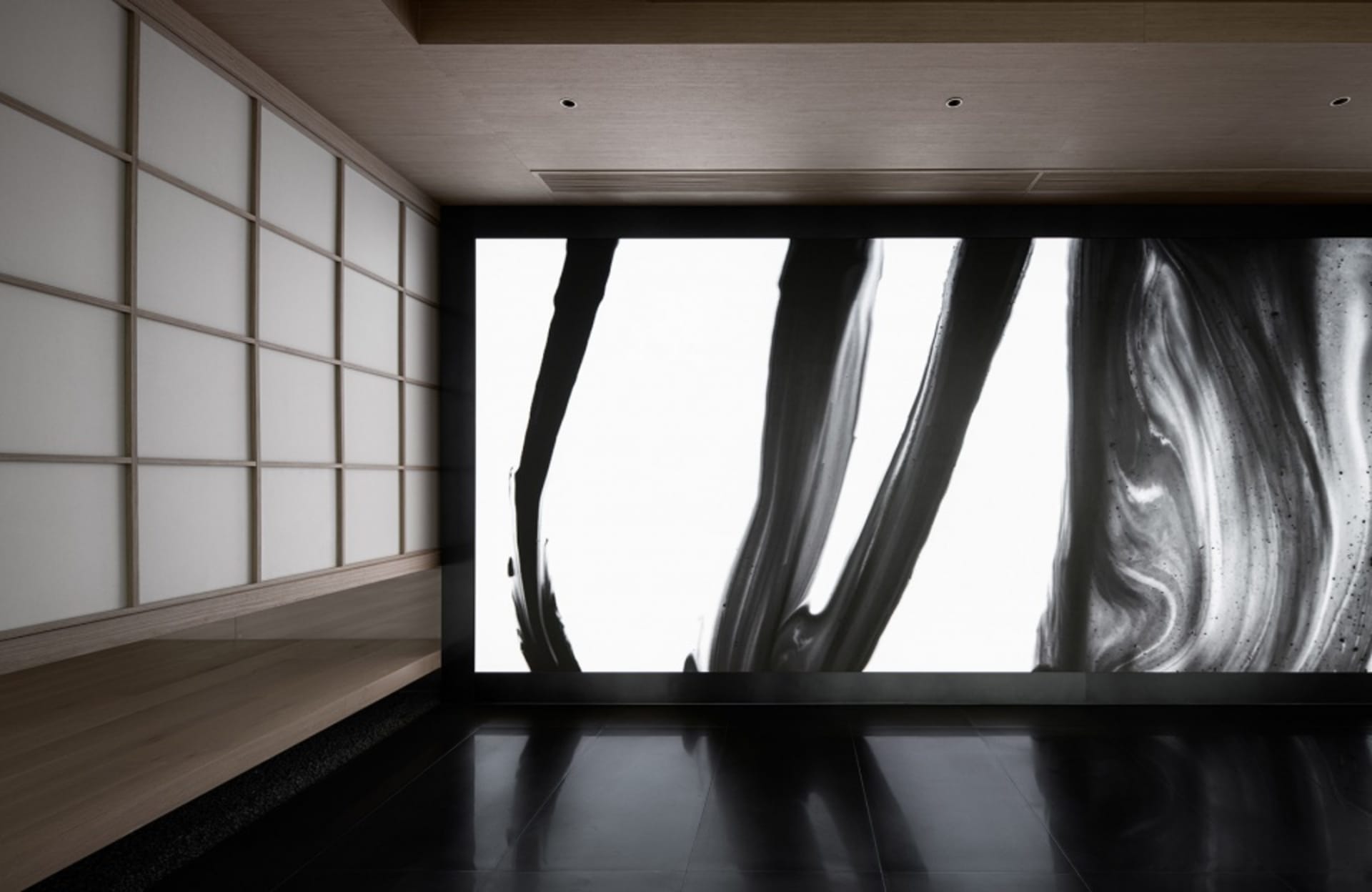 Two black and white paintings on a wall in a darkened room create a dramatic and thought-provoking atmosphere