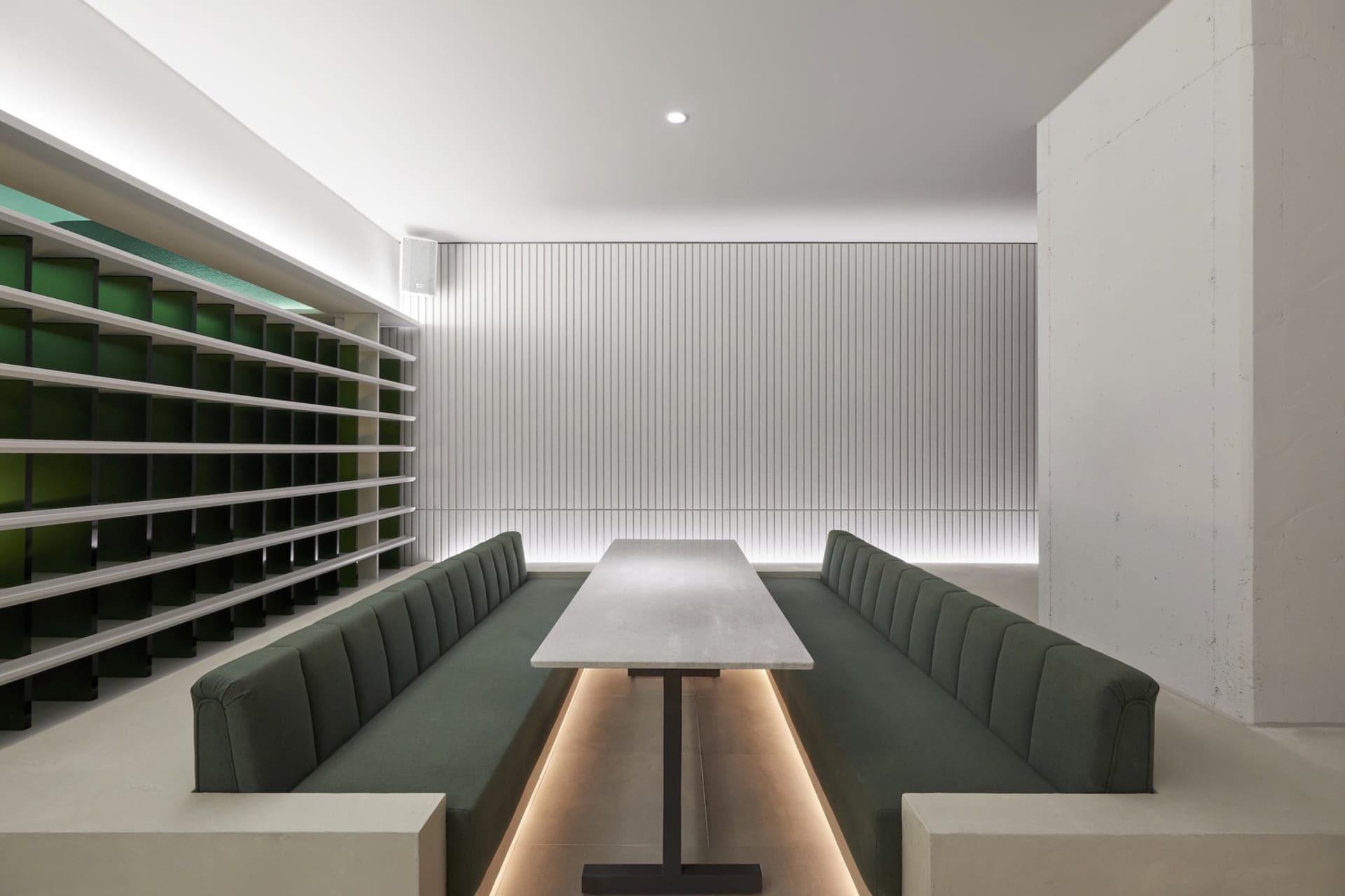 現代餐廳內部，木質餐桌環繞綠色椅墊座椅，自然光與人工照明充足明亮