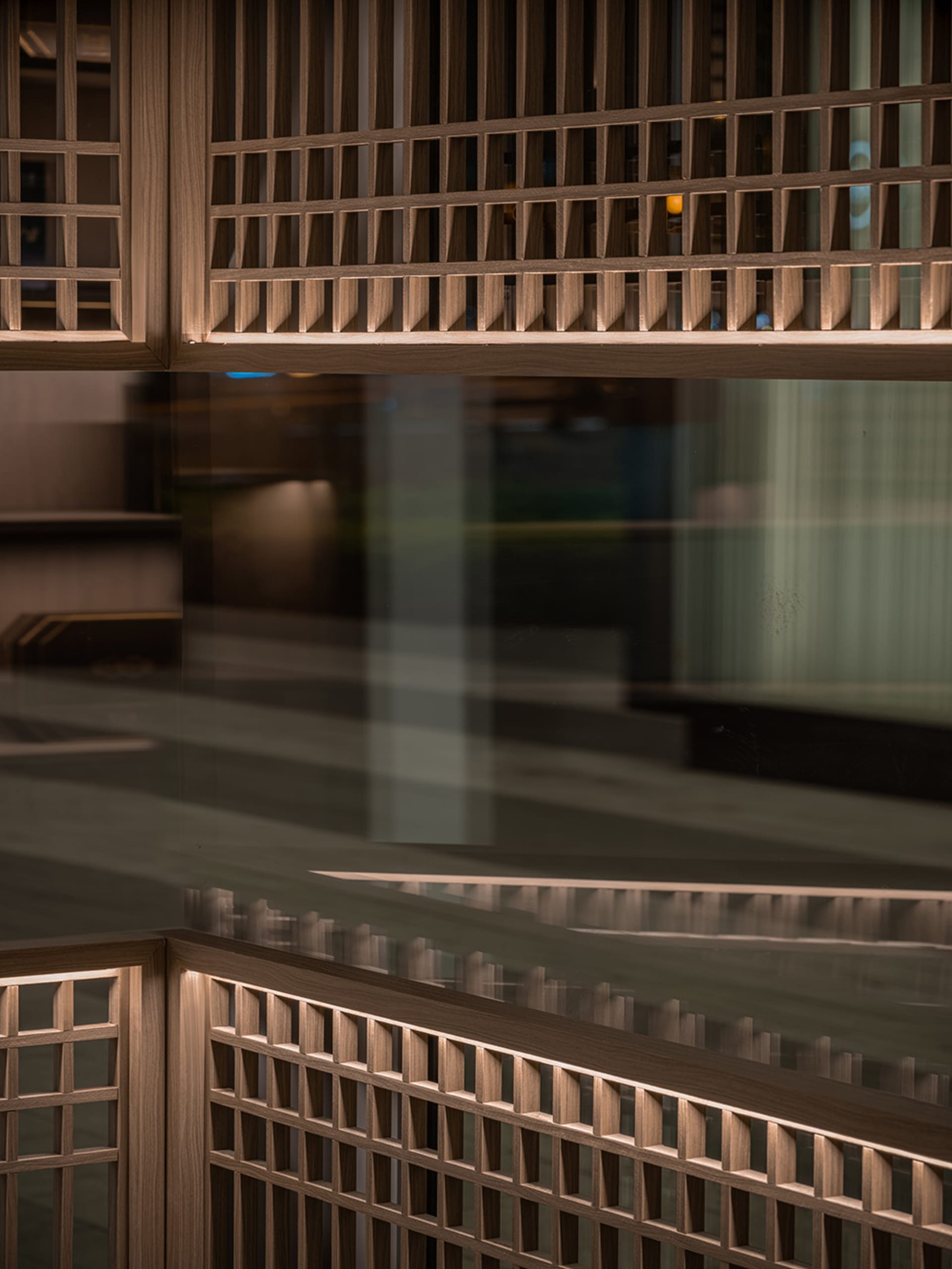 A modern hallway with a glass wall reflecting the surroundings, wooden panels on the walls, and well-lit space with natural or artificial light