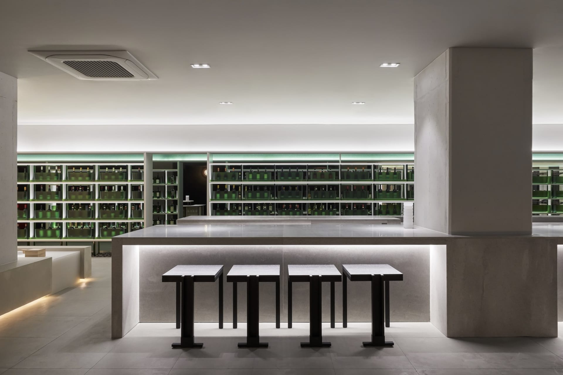 A luxurious bar area with a marble counter, stools, and bottles on display in a sophisticated and inviting environment