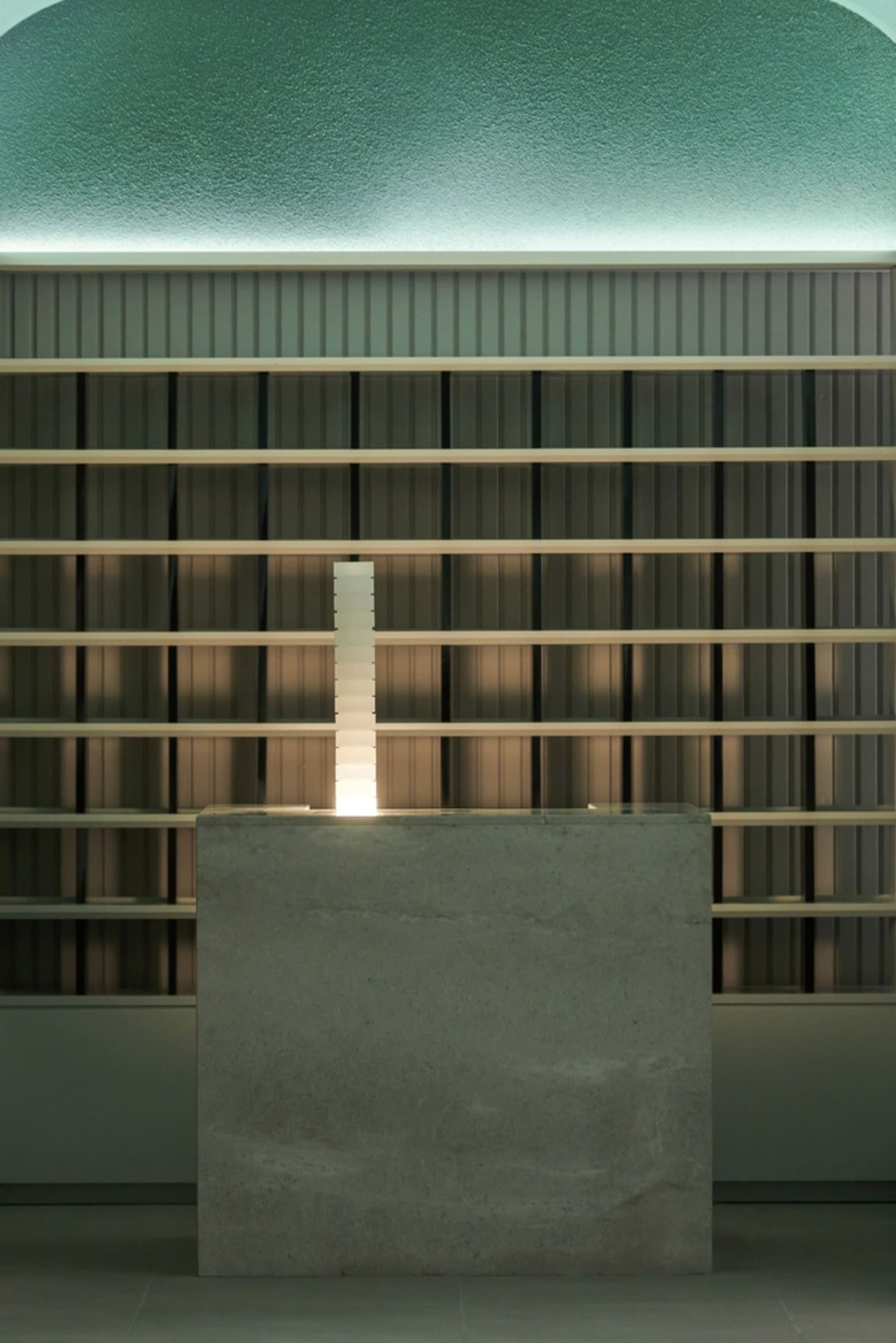 A stone table with a candle on top sits in front of a bookshelf filled with various books, creating a warm and inviting atmosphere for reading and relaxation