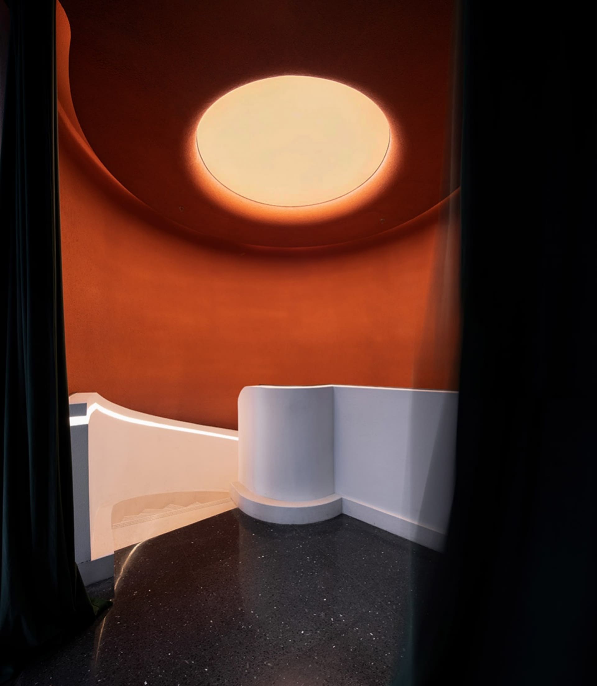 A bright and inviting modern room with a circular shape and a large glass window allowing natural light to enter