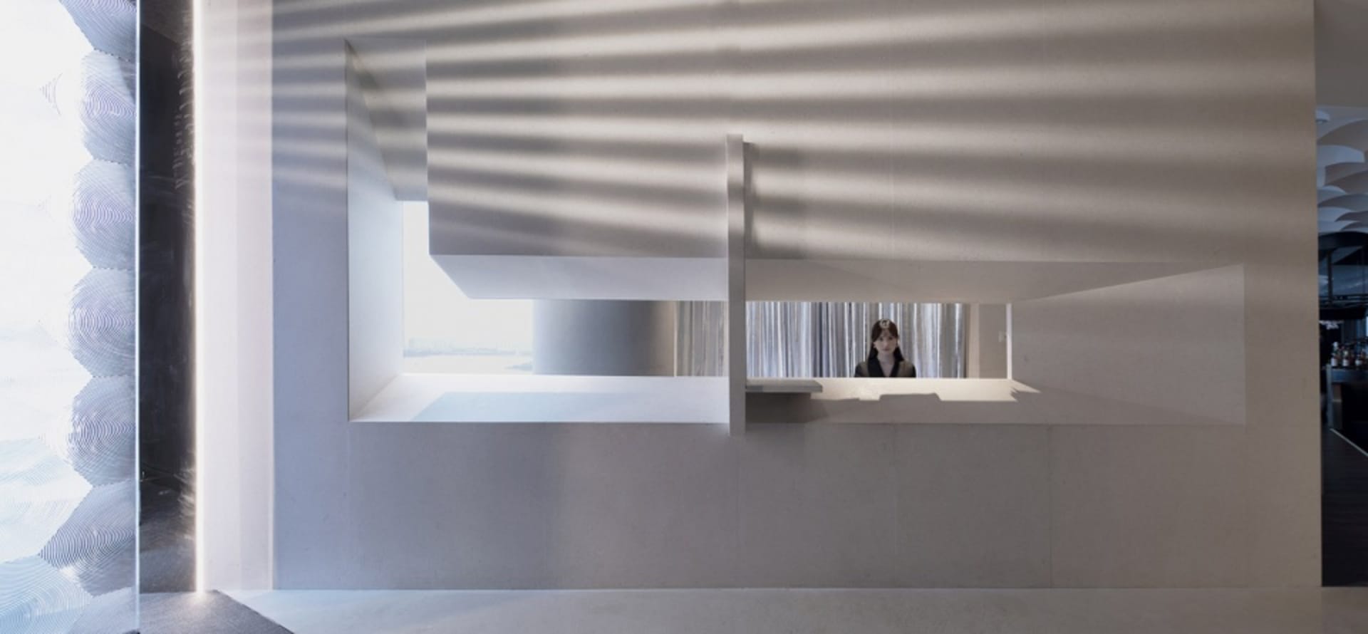 Office space with a receptionist's desk made of concrete, two chairs, and natural light from a window