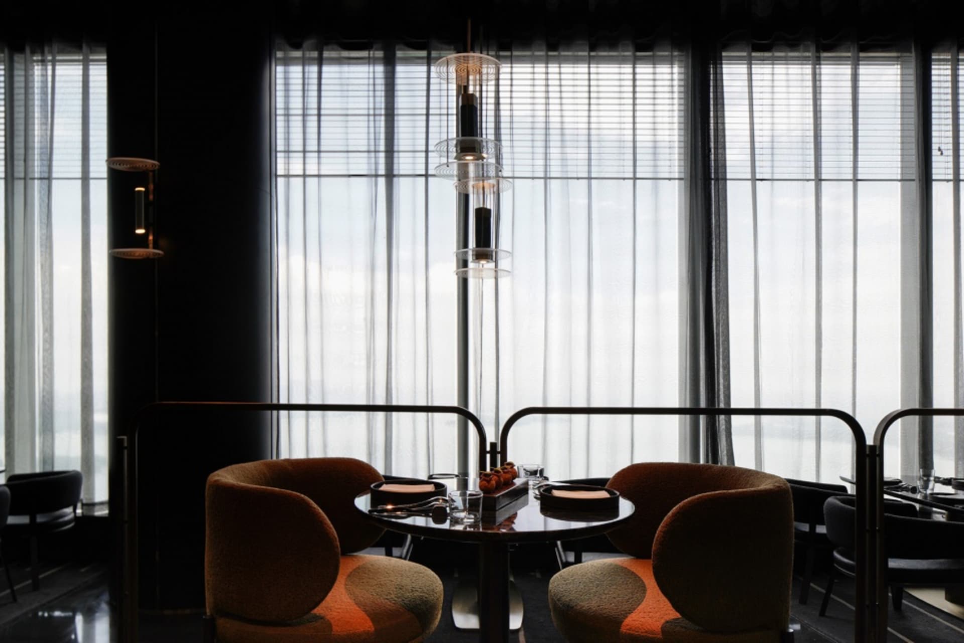 A formal dining area with two round tables and four chairs, featuring place settings and decorative accents, set in a well-lit space