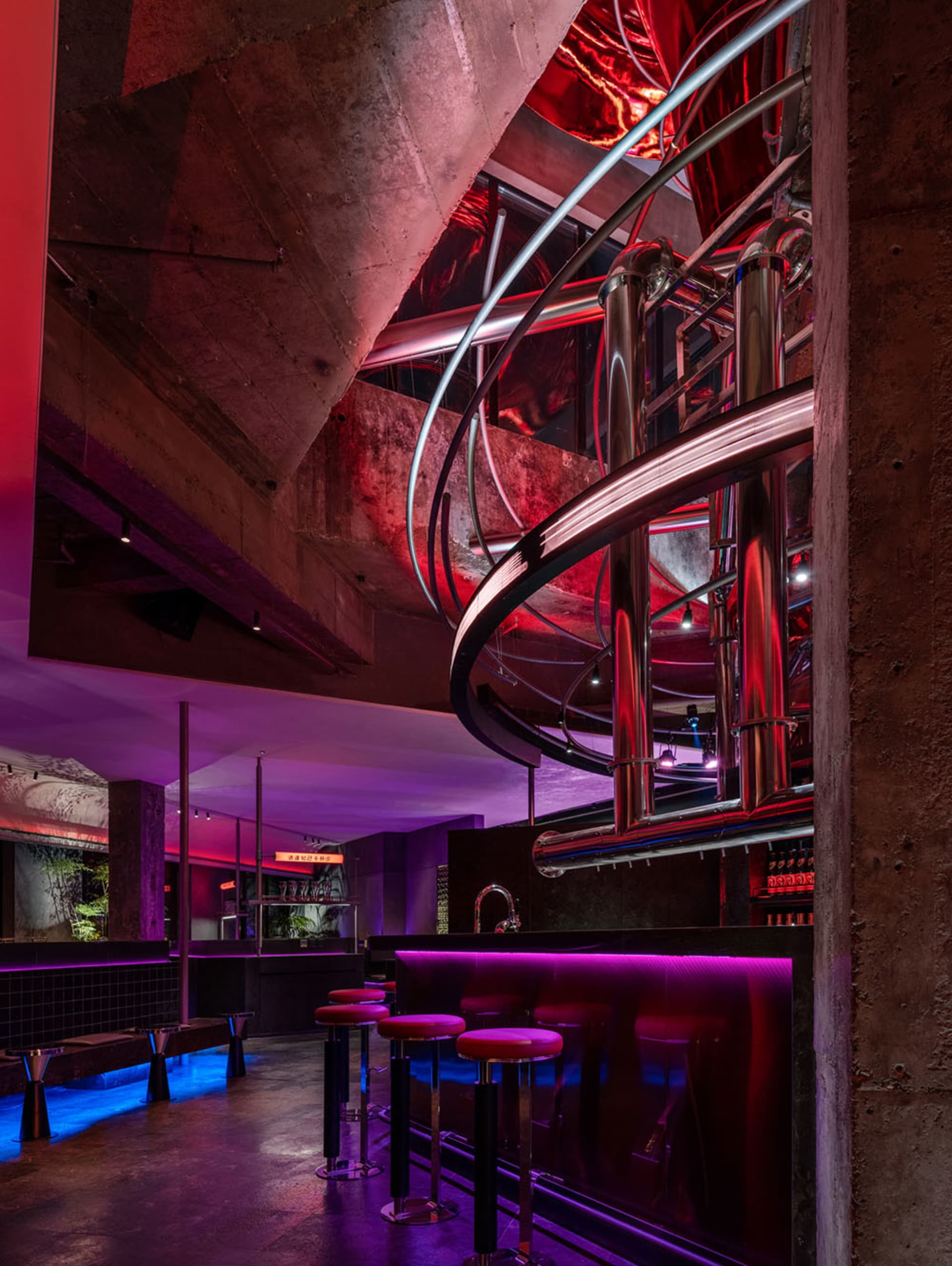 A cozy bar area with a spiral staircase, comfortable seating, and bottles on display, creating an inviting atmosphere for socializing and relaxation