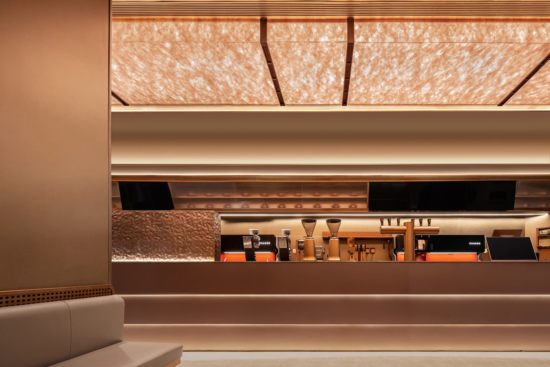 Modern bar with a counter, TV screens, and a warm atmosphere