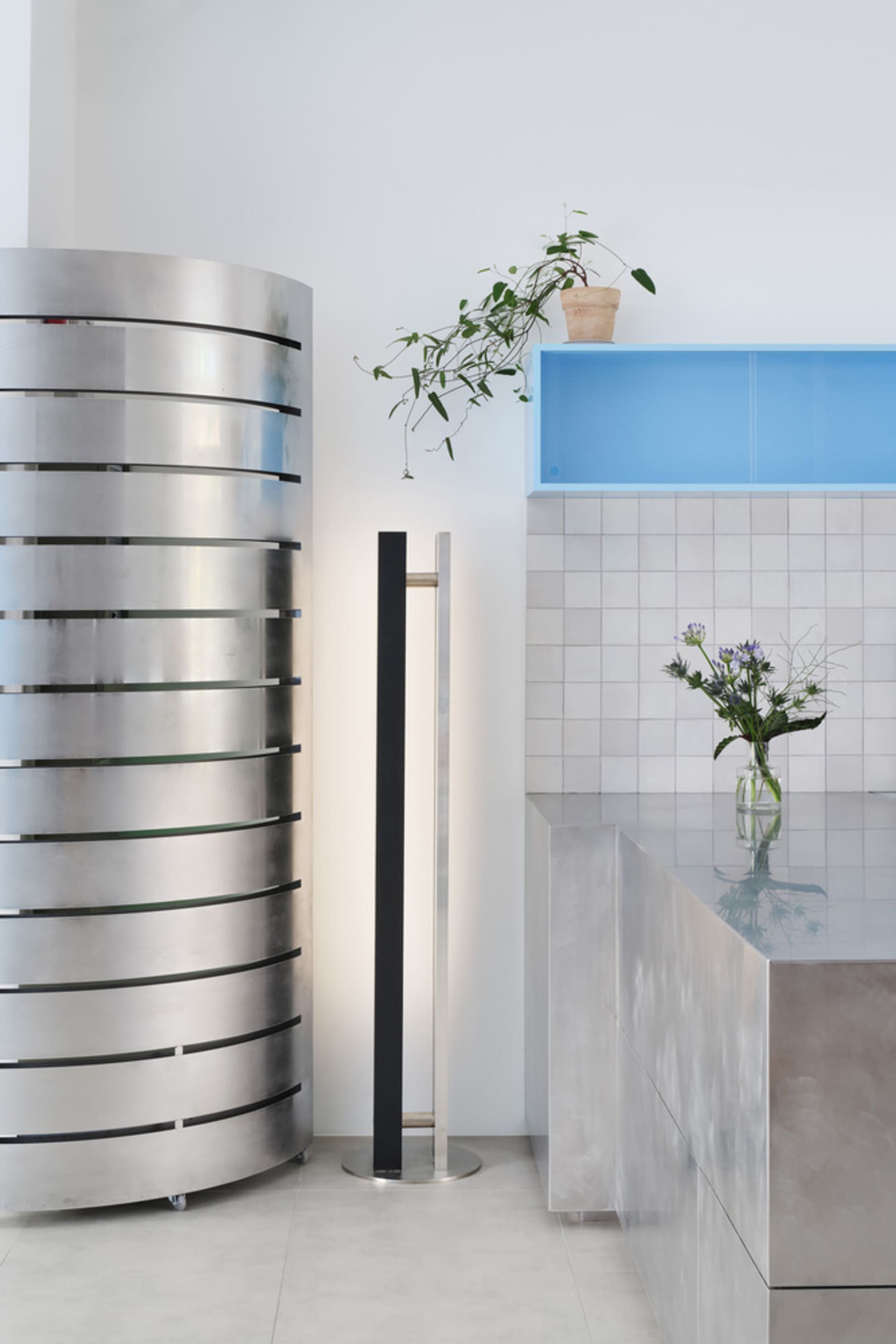A clean and organized kitchen space with a countertop, potted plant, vases, and a bottle, emphasizing functionality and aesthetics