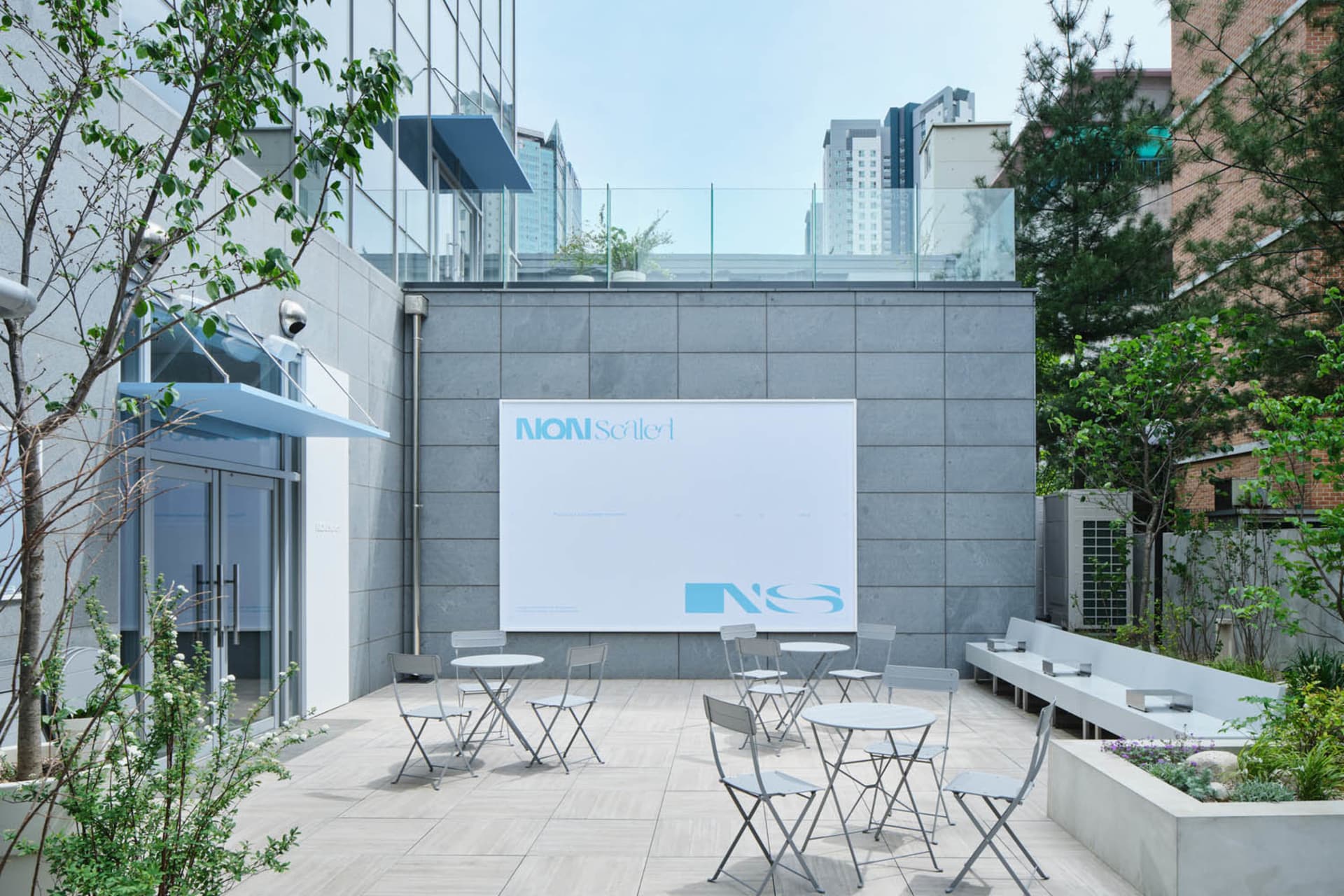 A patio area with chairs and dining tables on a tiled floor, creating a comfortable outdoor space for dining and gatherings