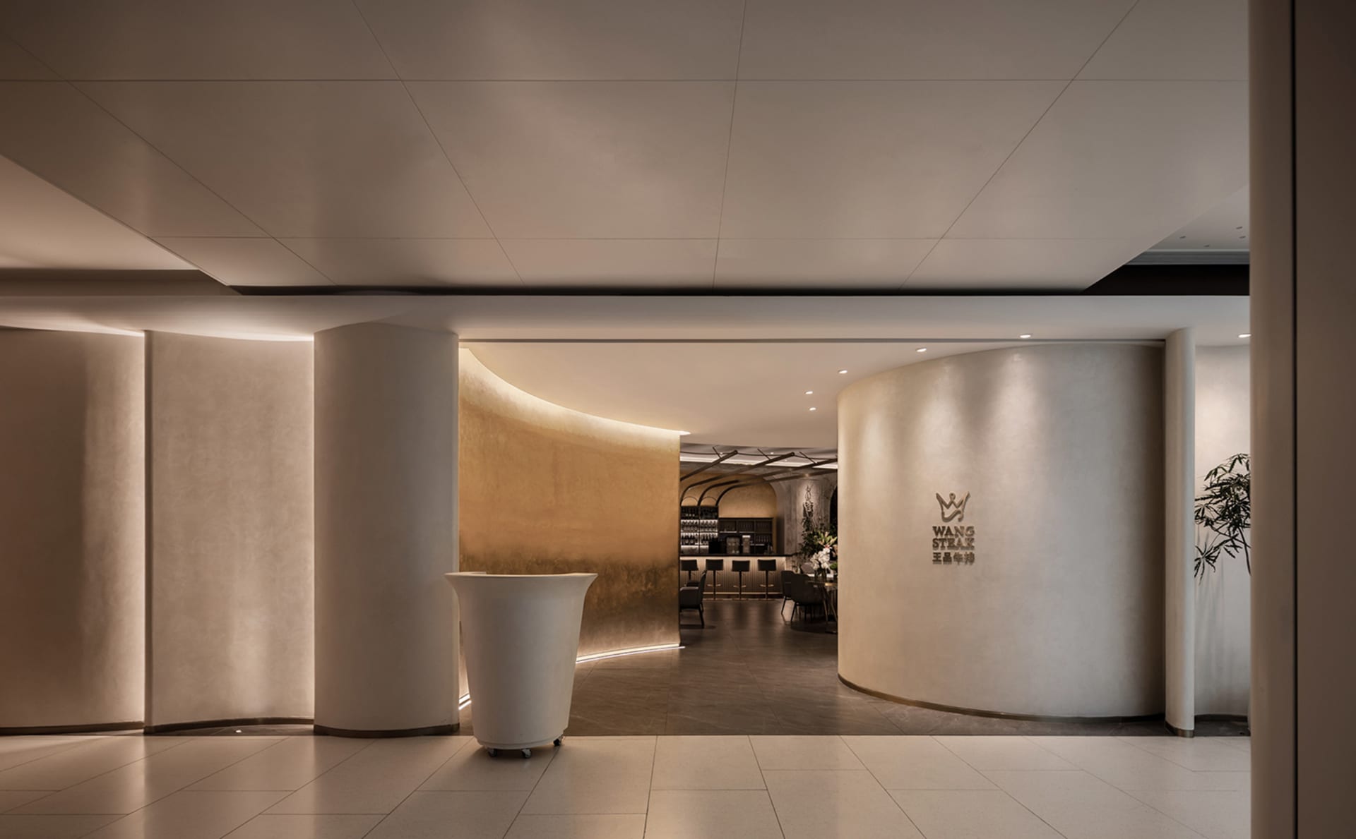 Elegant cafe interior with a large white vase, seating areas, and a dining table, featuring a modern aesthetic with white as the dominant color