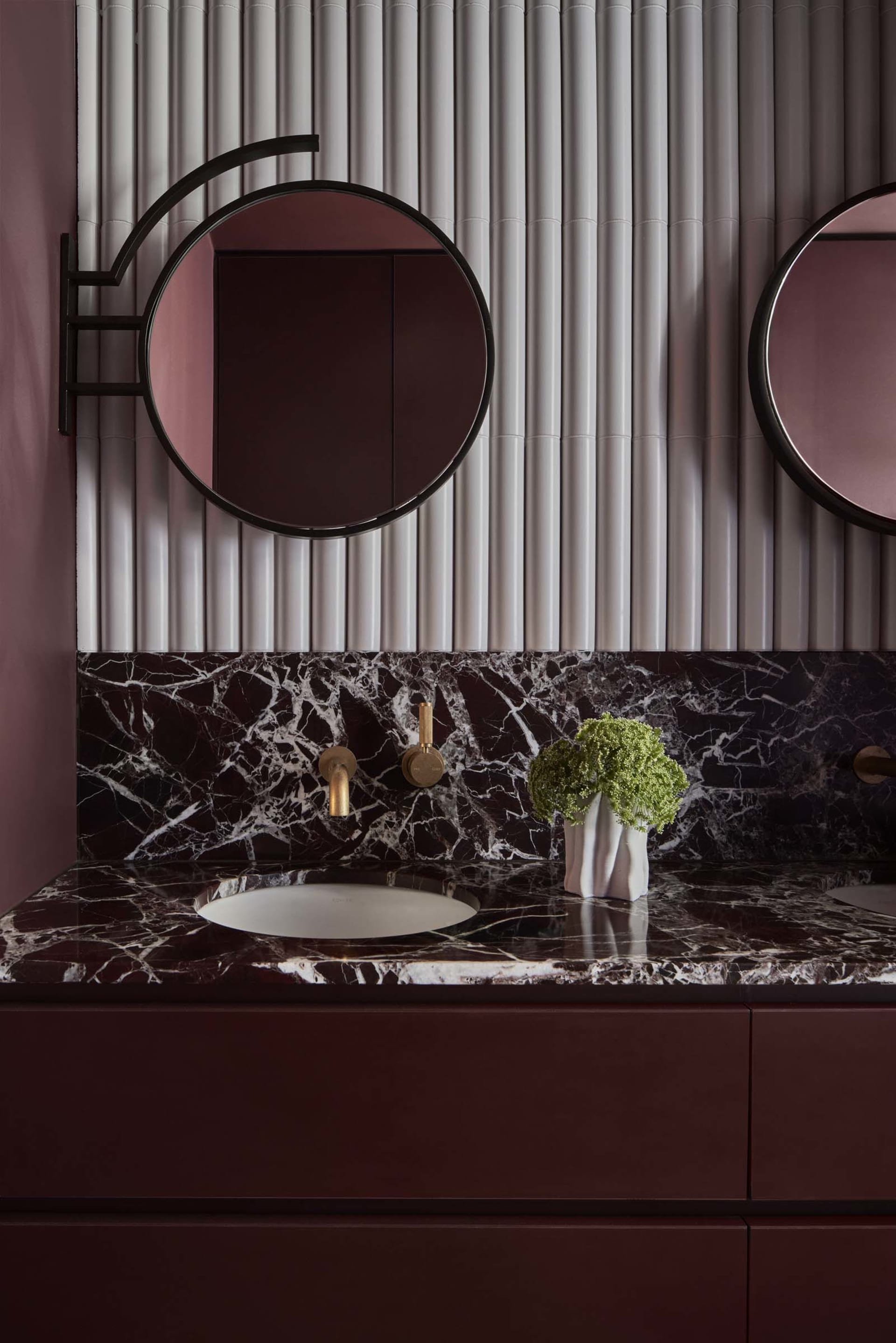 Modern bathroom with a double sink, mirror, and elegant decor, featuring vases and well-lit design