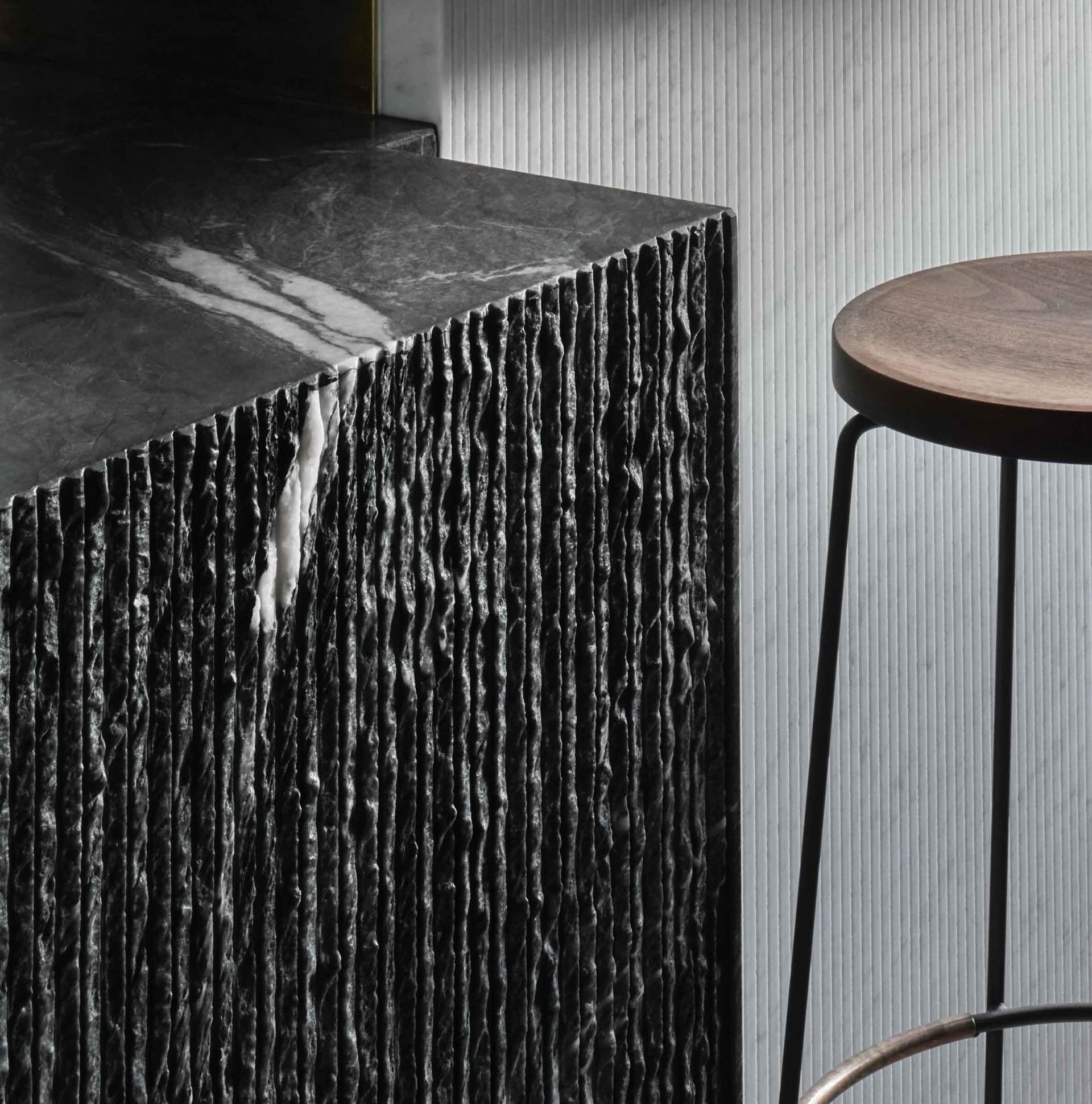 A modern kitchen with a black marble countertop, two stools, and a sleek design