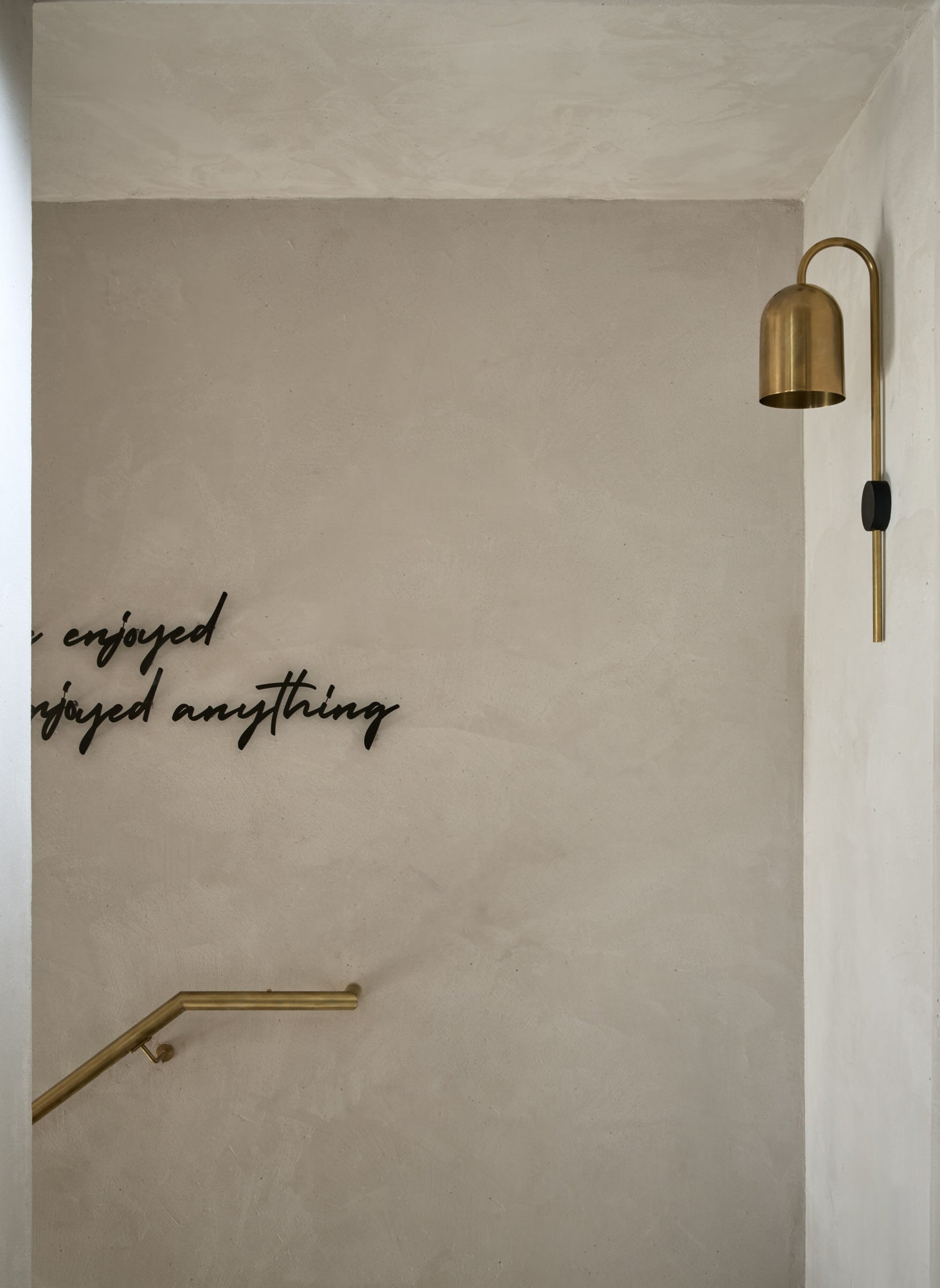A stairwell with industrial concrete steps, a gold lamp, and a sign reading 'I have enjoyed everything'