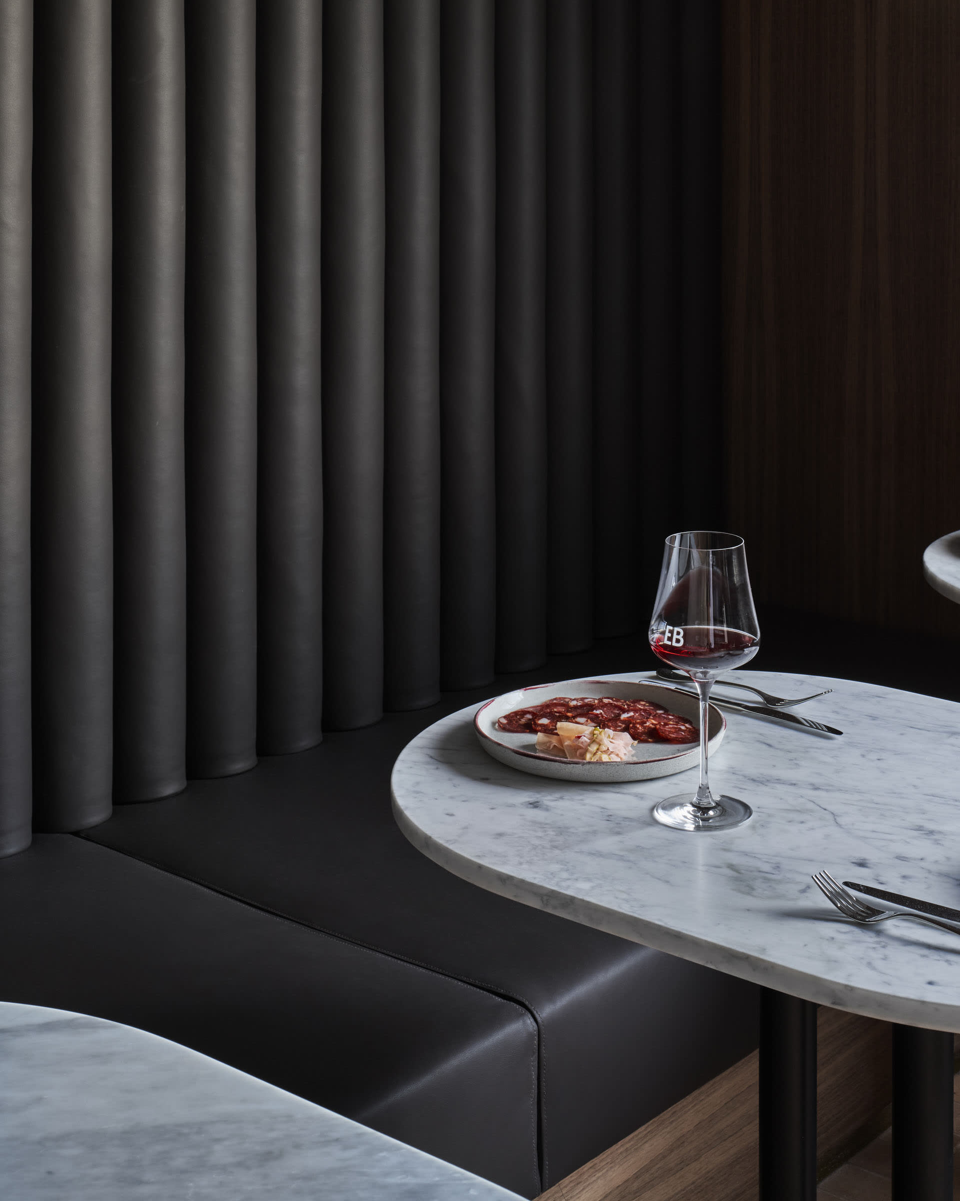 A single-occupant dining setup in a cozy restaurant with a wooden table, wine glass, and plate of food