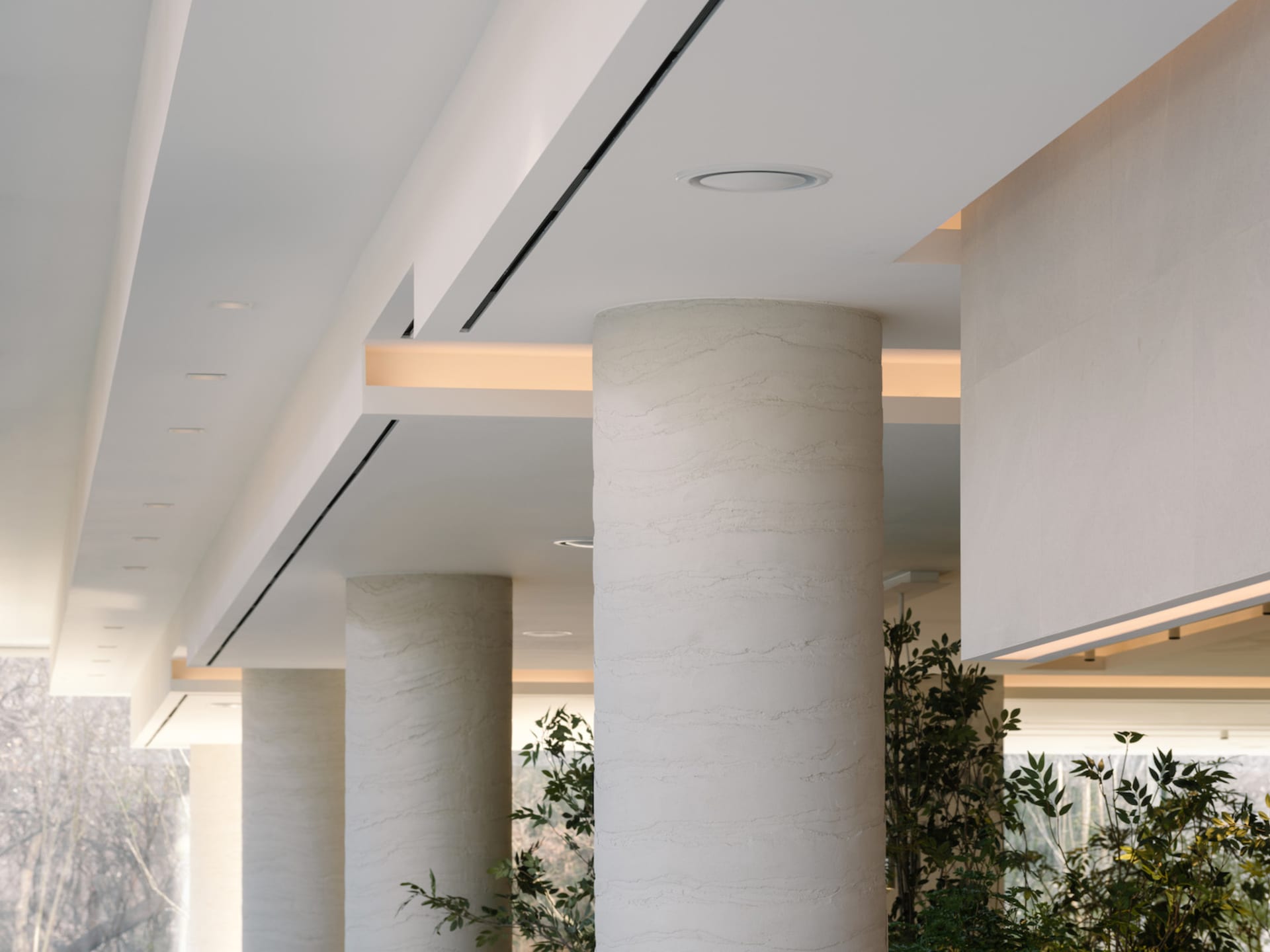 A grand, well-lit space with marble pillars, possibly with natural sunlight and artificial lighting, creating a sense of elegance and grandeur