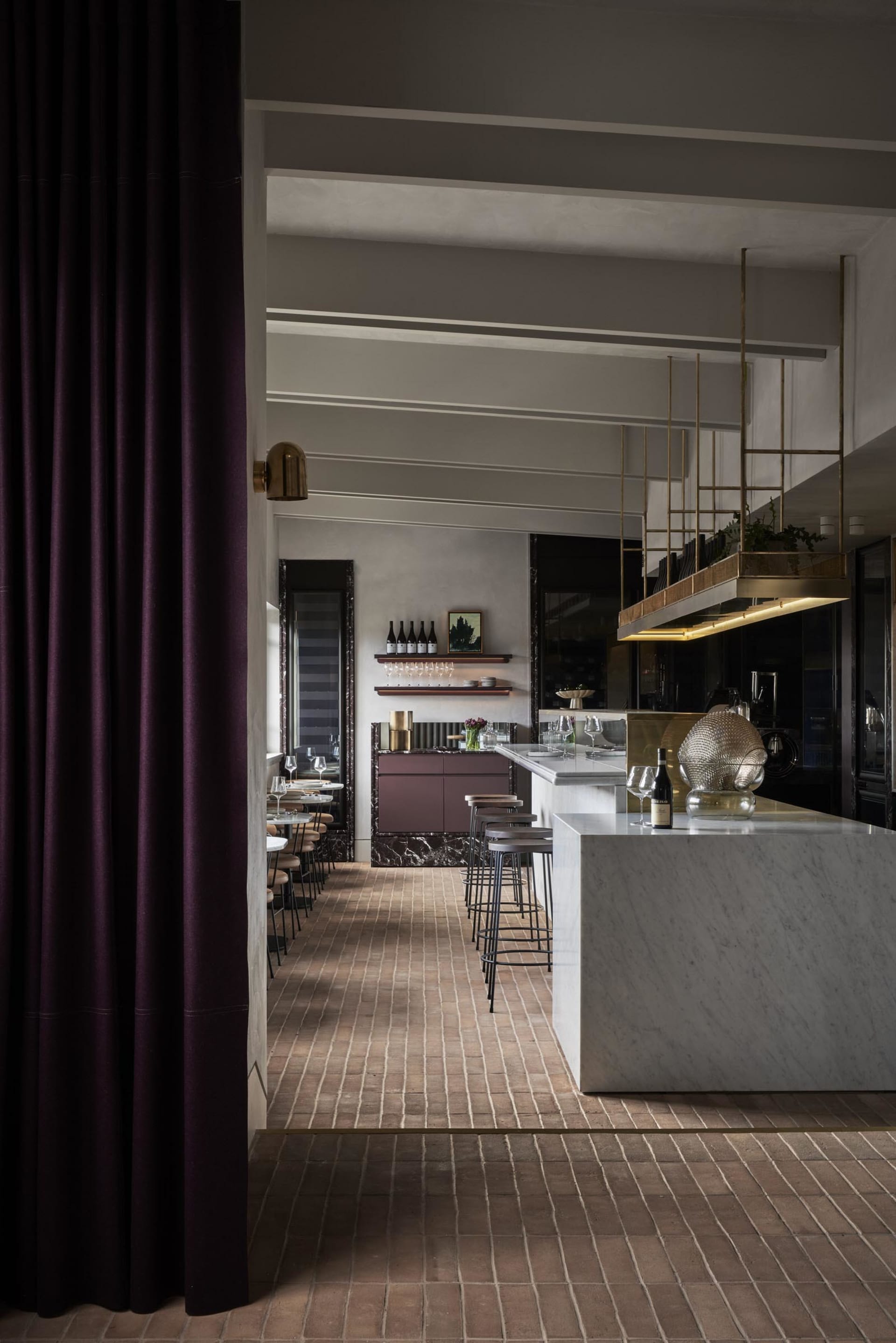 Elegant restaurant interior with marble countertops, a wine rack, and wooden accents, featuring a comfortable dining area and kitchenette