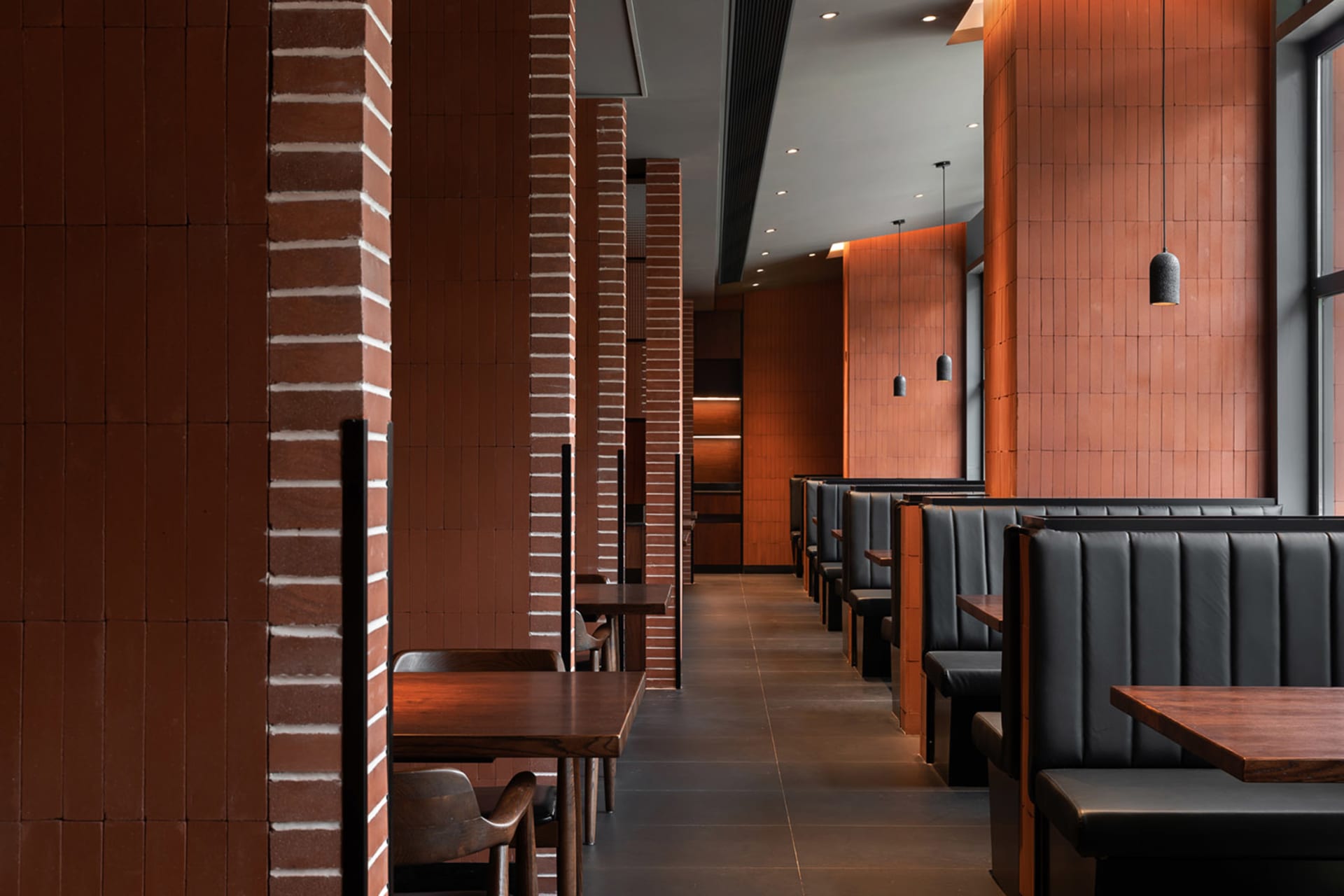Warm restaurant interior with brick walls, wooden tables, and chairs, creating a comfortable atmosphere for diners