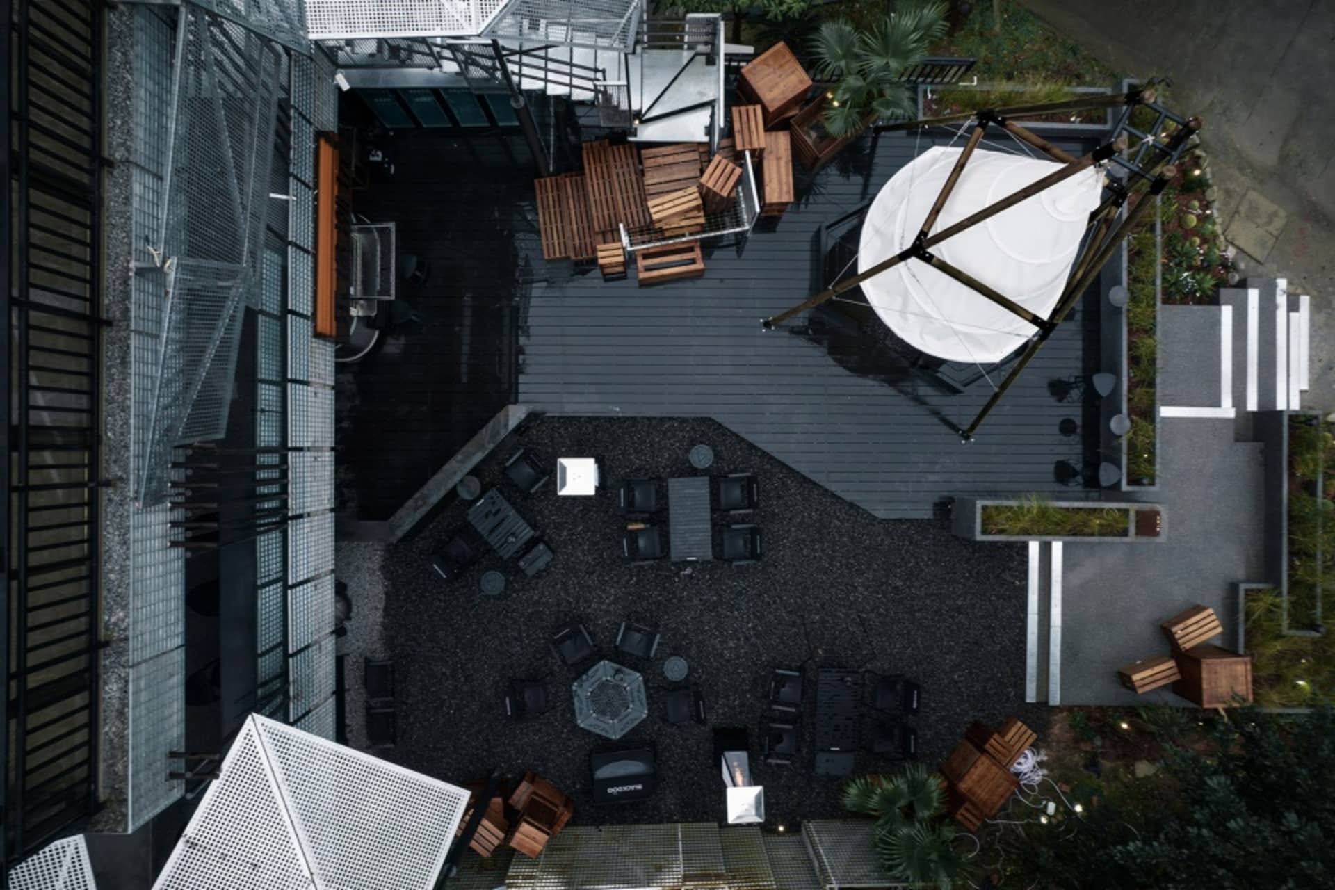 A modern restaurant space with black furniture, umbrellas, and a mix of seating areas