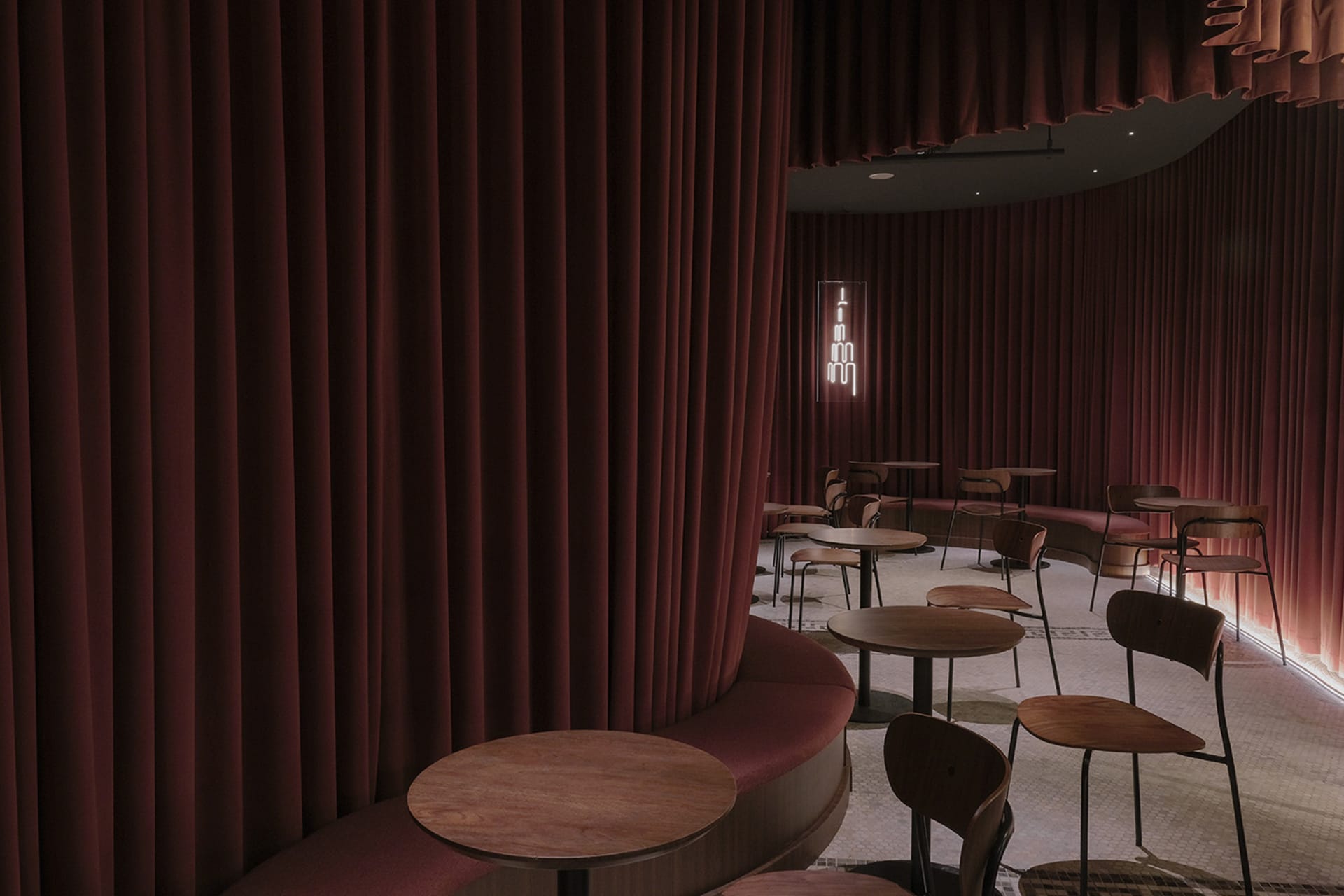 Cozy restaurant interior with red curtains, wooden tables, and comfortable seating
