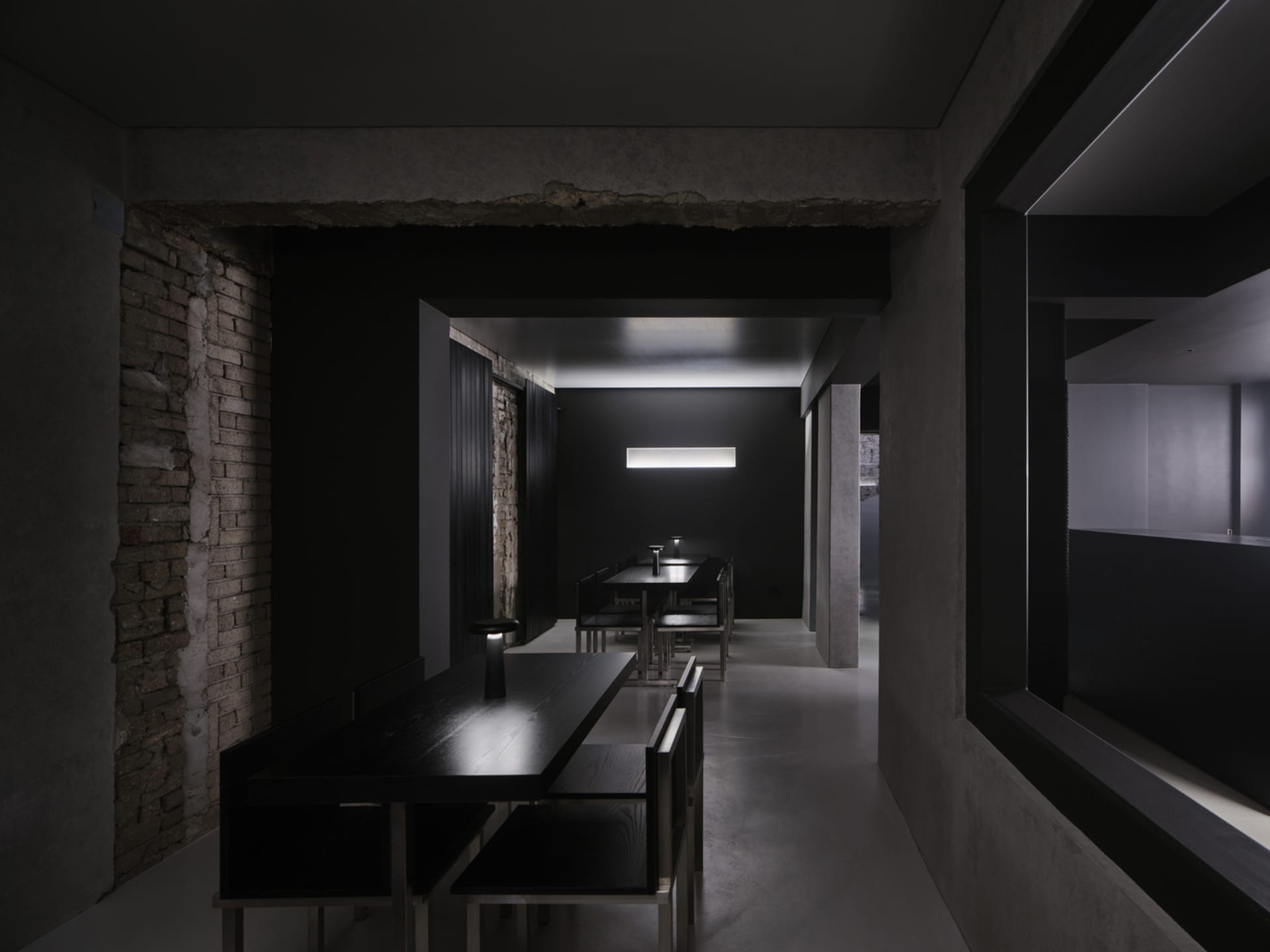 Empty modern restaurant with black interior, dining tables, and chairs, creating a sophisticated atmosphere