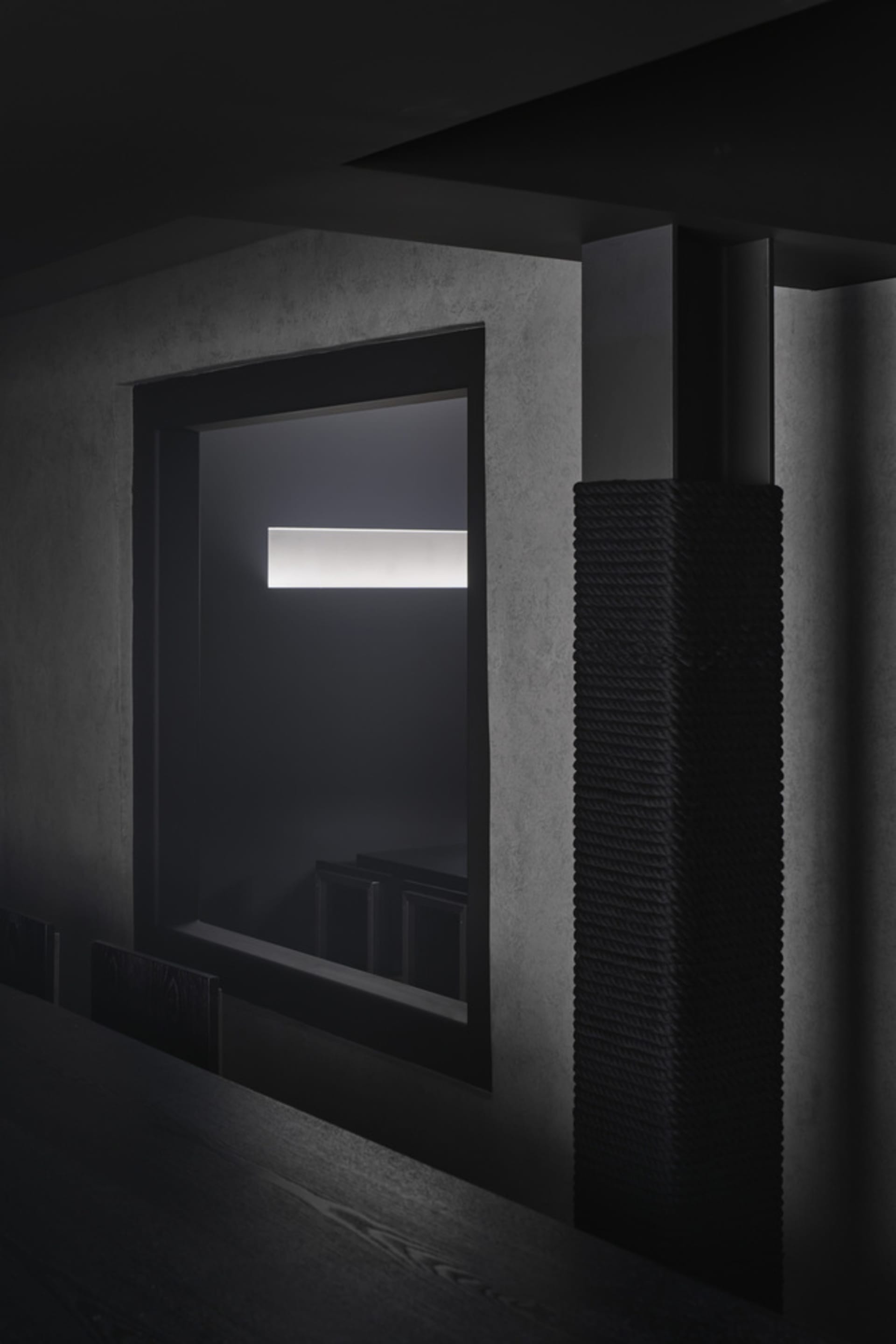 A calm room with black walls, a window, and a mirror reflecting the view outside, with two chairs placed near the window