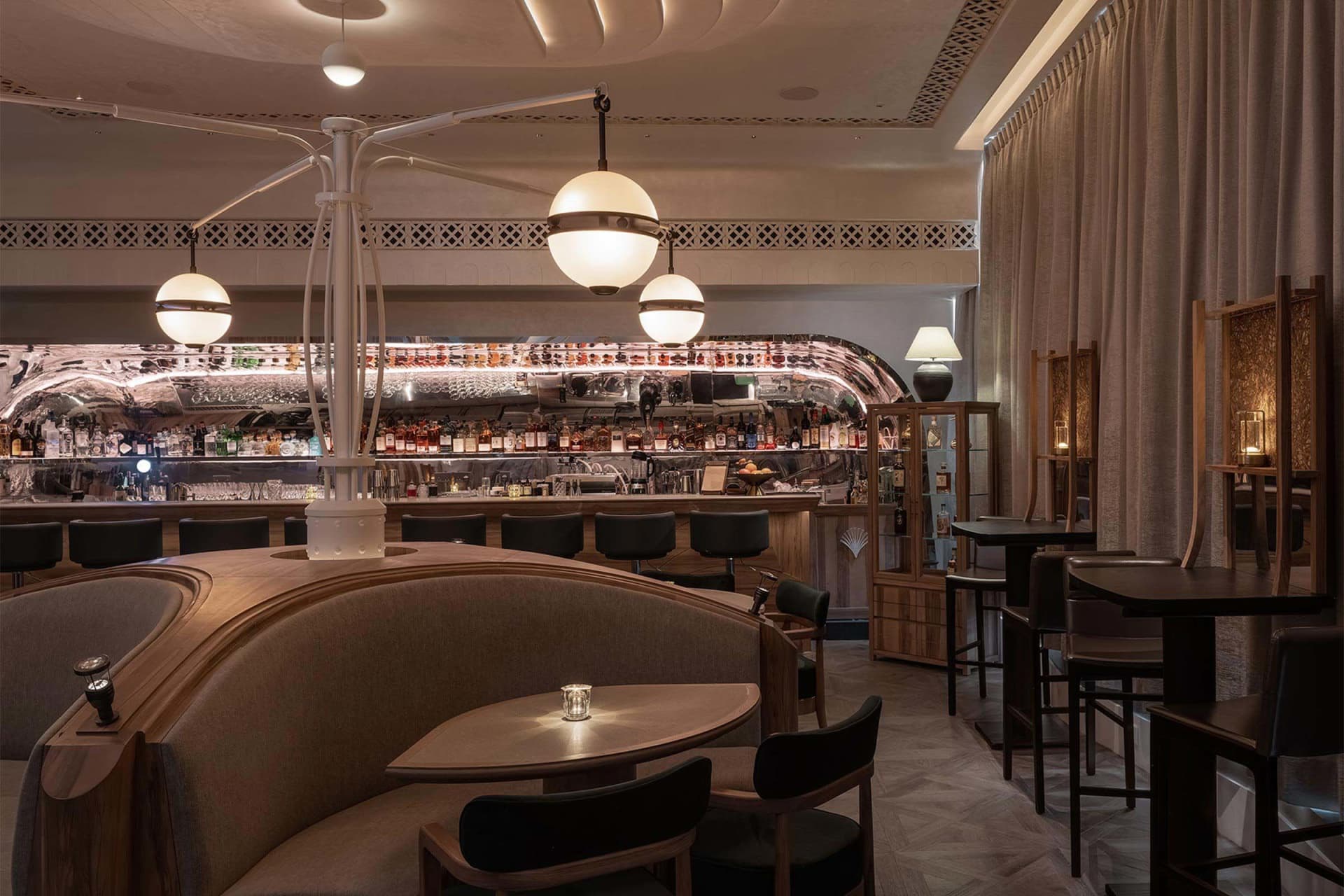 A cozy bar area with a long wooden dining table and chairs, a bar counter with bottles and wine glasses, and an inviting atmosphere