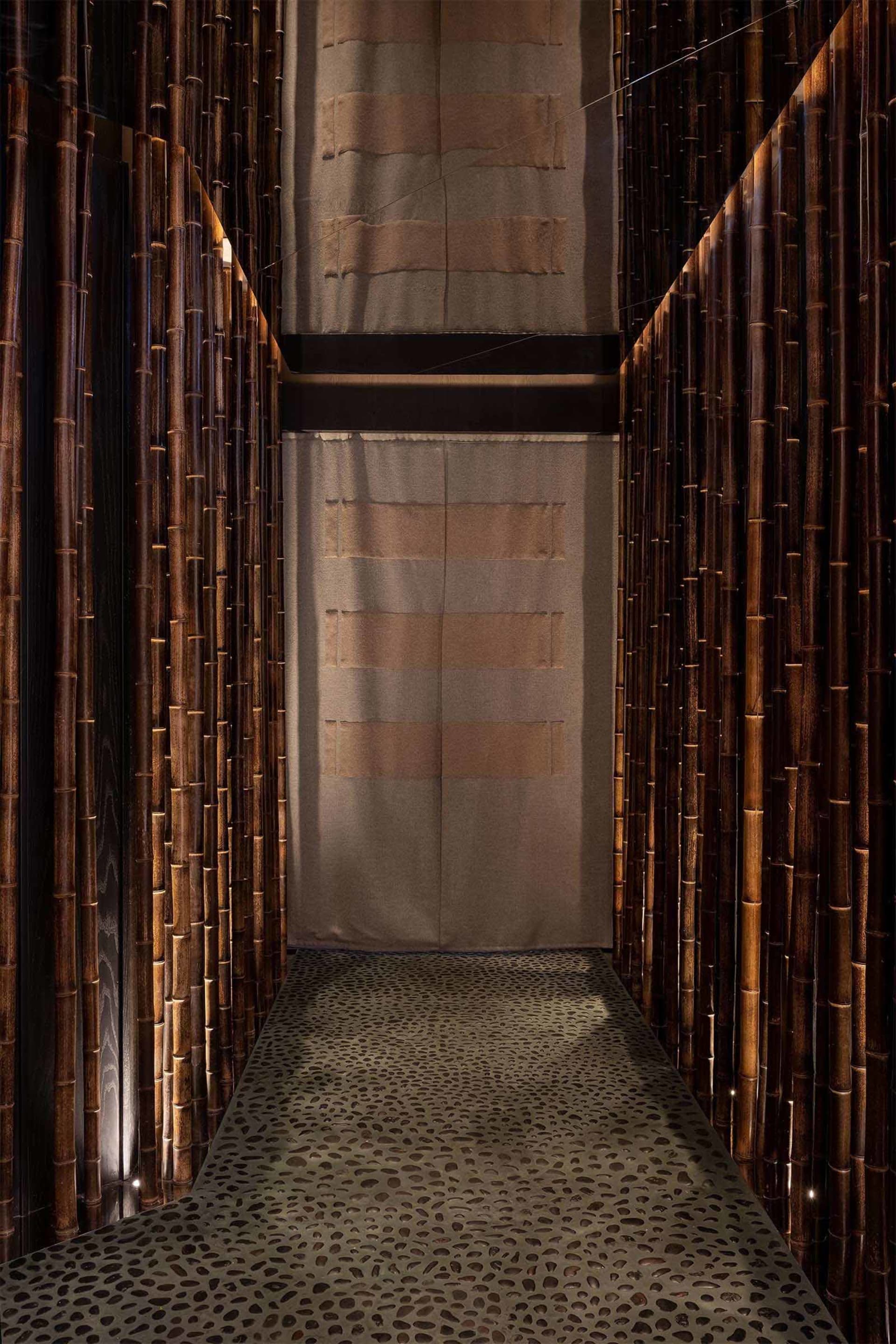 A warm and inviting hallway with bamboo walls, carpeted floor, and bamboo pillars