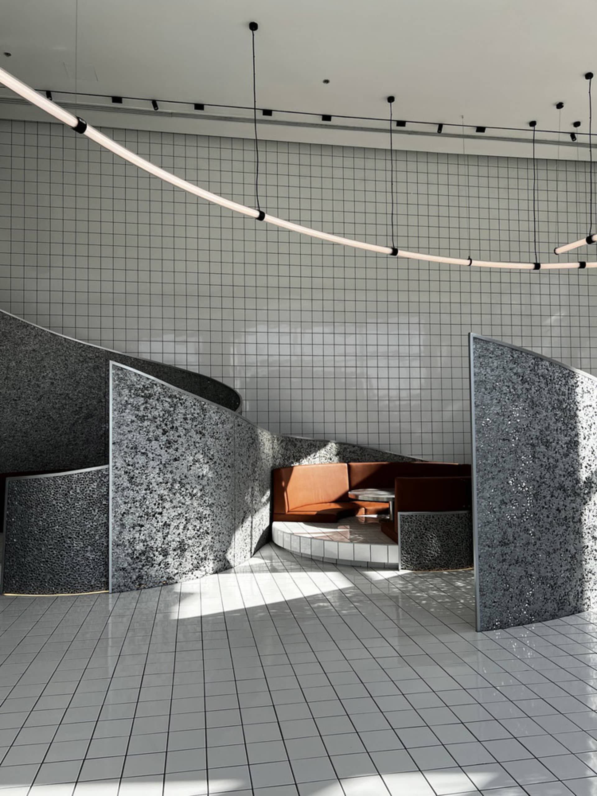 Bright and inviting open space with a curved wall, chairs, and natural light from windows