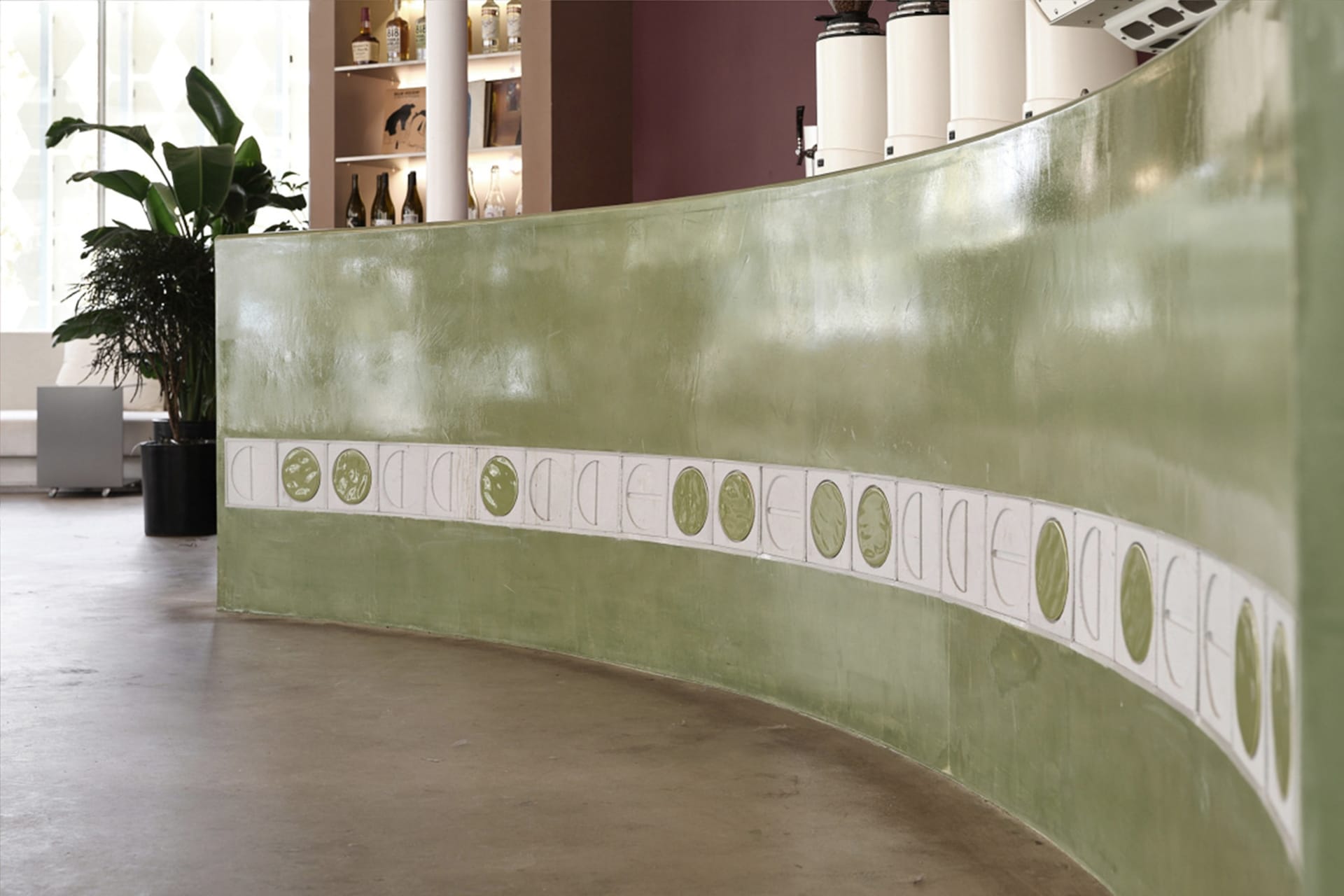 Modern interior design concept featuring a curved green wall with decorative elements and scattered bottles, creating a unique and stylish atmosphere