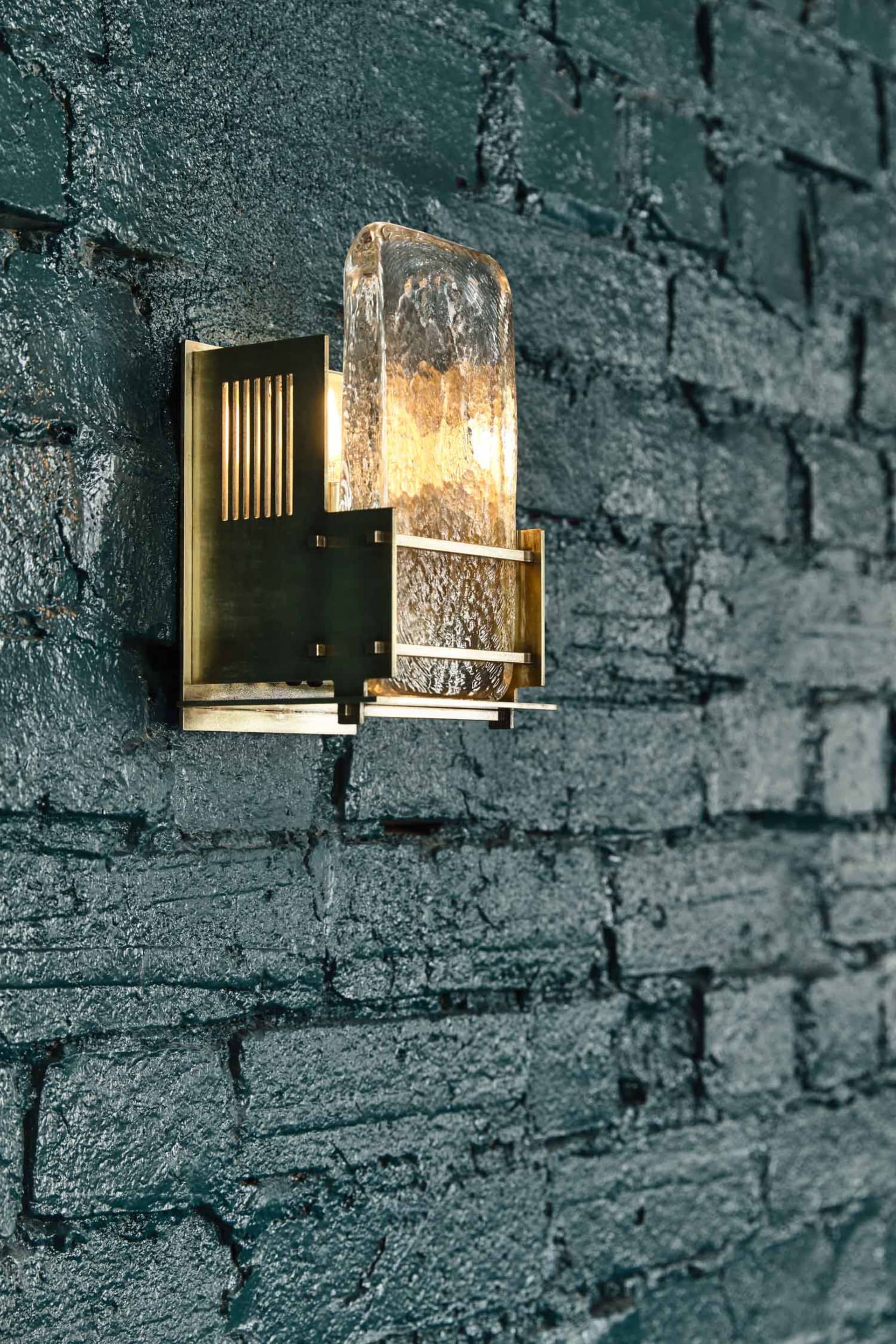 A dimly lit room with an exposed brick wall and two different light fixtures, one with a glass covering and the other a simple metal fixture