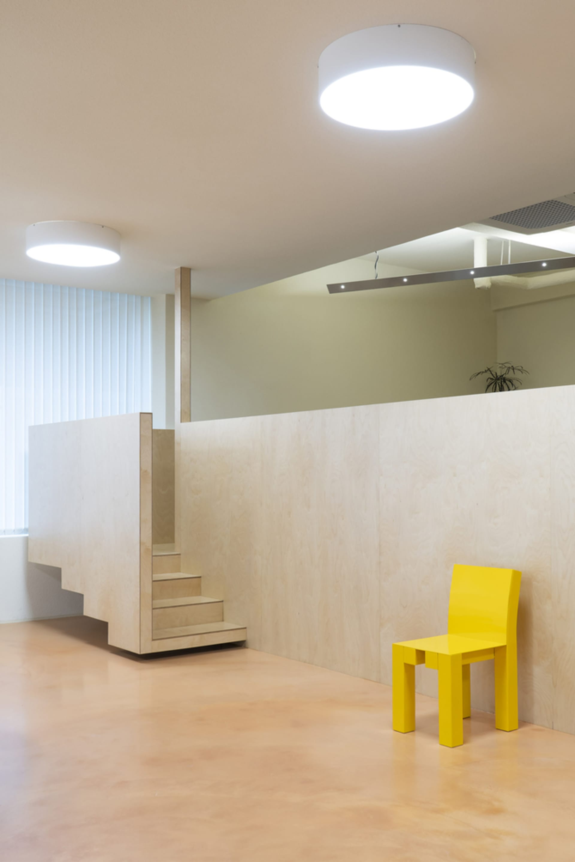 Cozy interior space with wooden walls and floors, a staircase, and a potted plant, creating a warm and inviting atmosphere