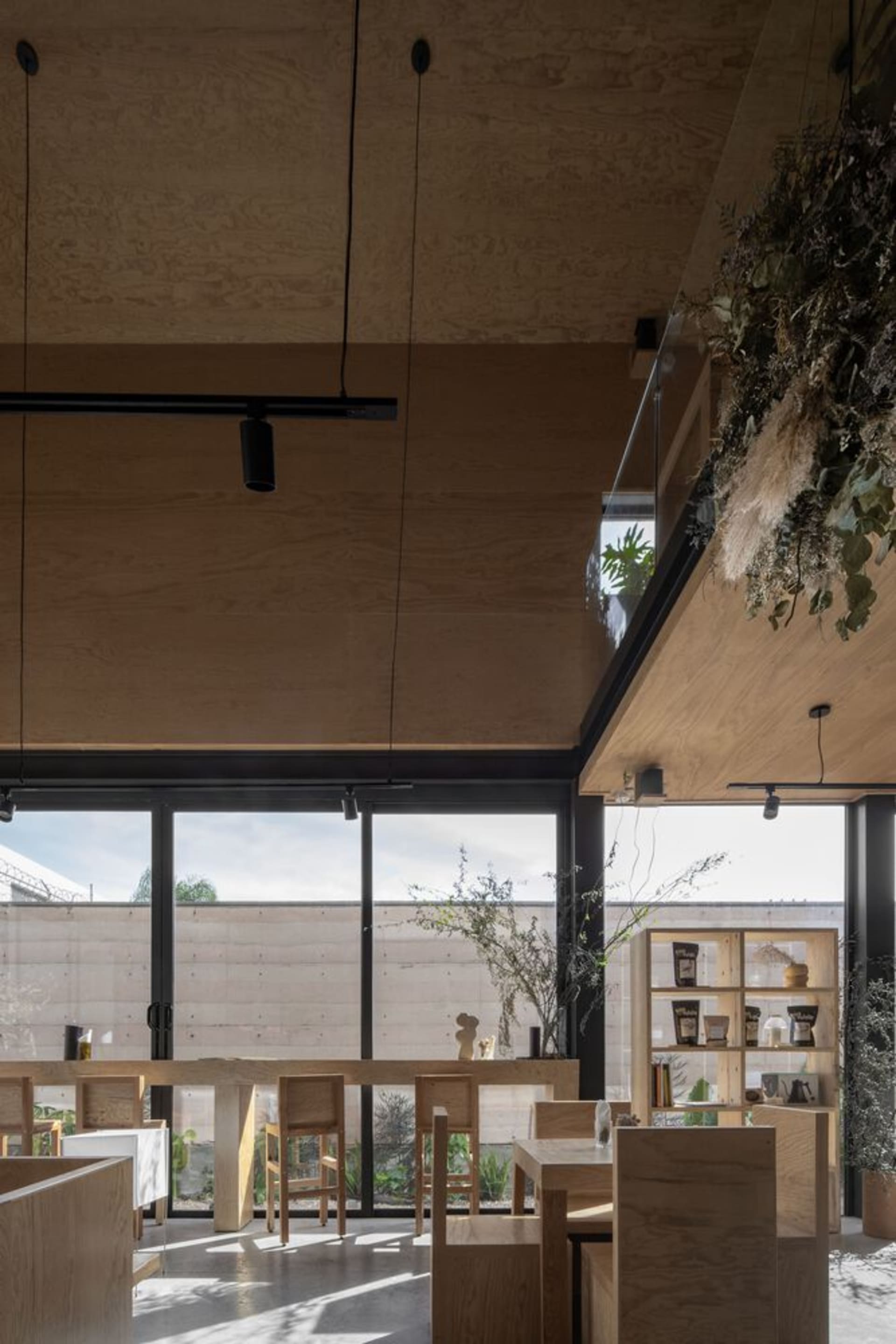 Cozy living area with wooden floors and walls, featuring chairs, a dining table, a potted plant, and books, creating a warm and inviting atmosphere