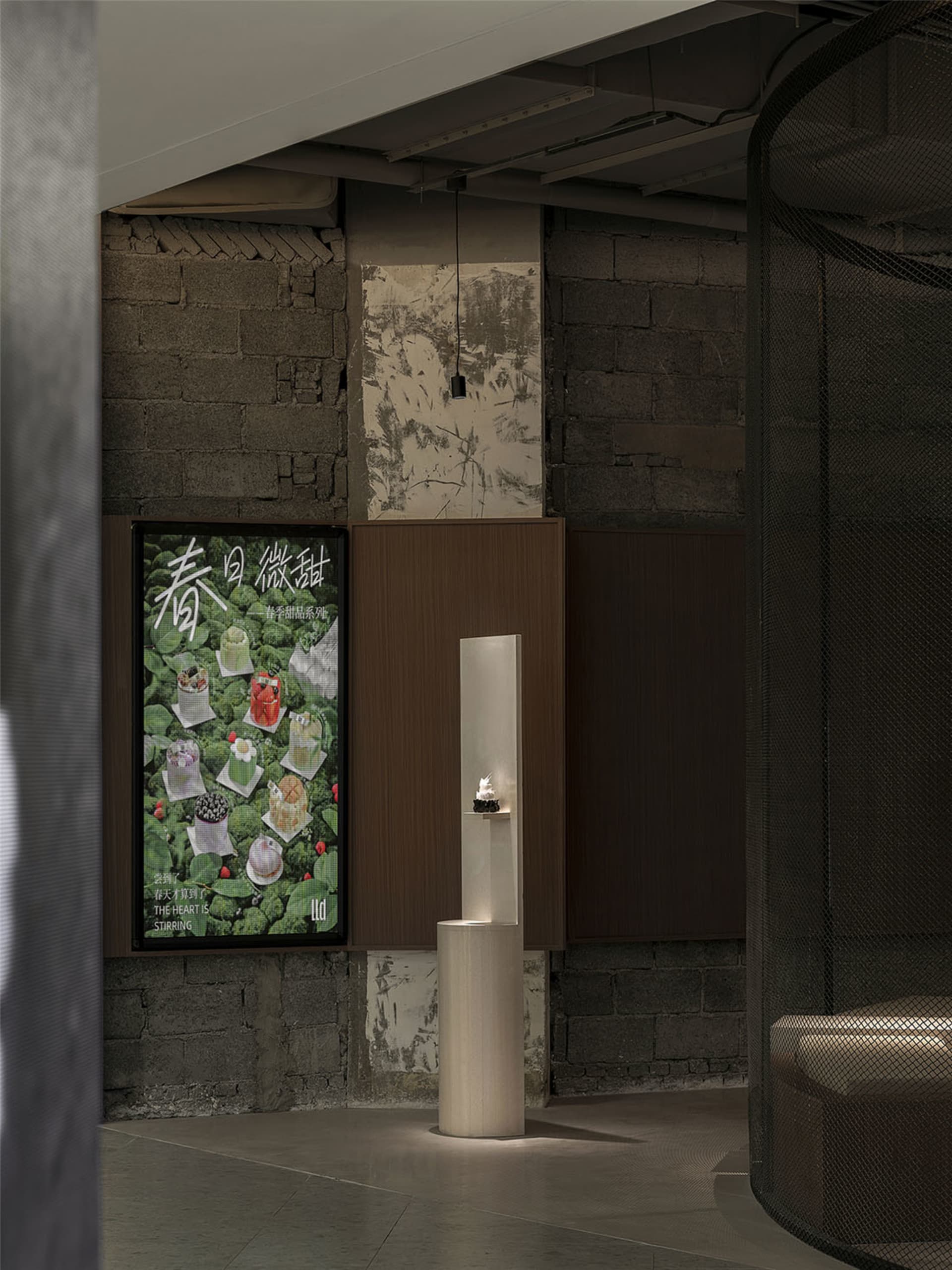 A modern interior space with a white pillar in the center, featuring two posters on the wall with a minimalist design