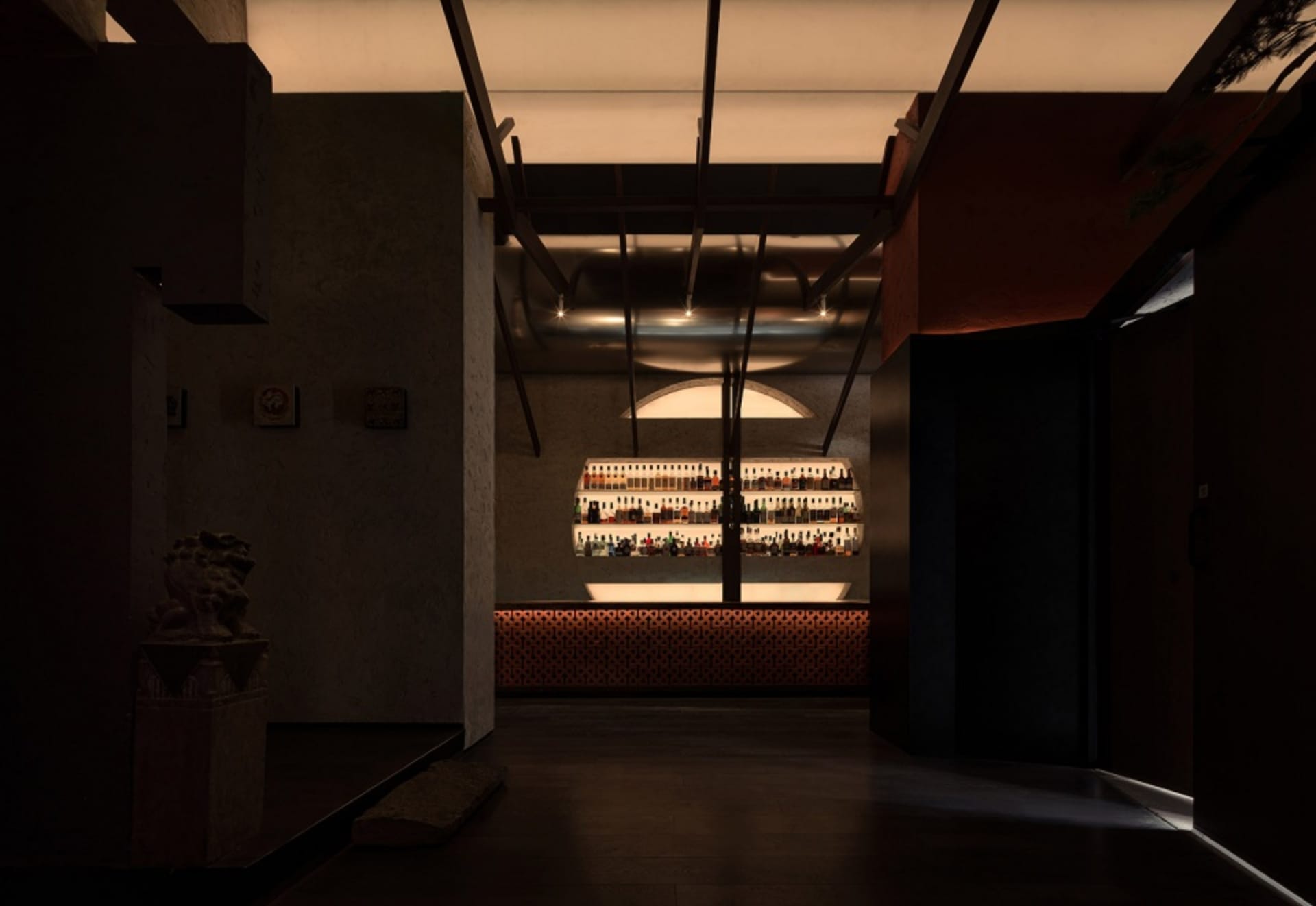 A cozy bar area with a long wooden counter, bottles of liquor, and wine glasses, creating a warm and inviting atmosphere for socializing