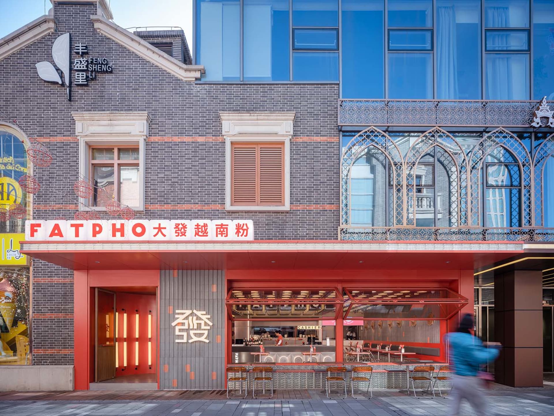 熱鬧亞洲餐廳，紅色牆面、橘色邊飾，餐廳區域有多張桌椅，有人坐有人站