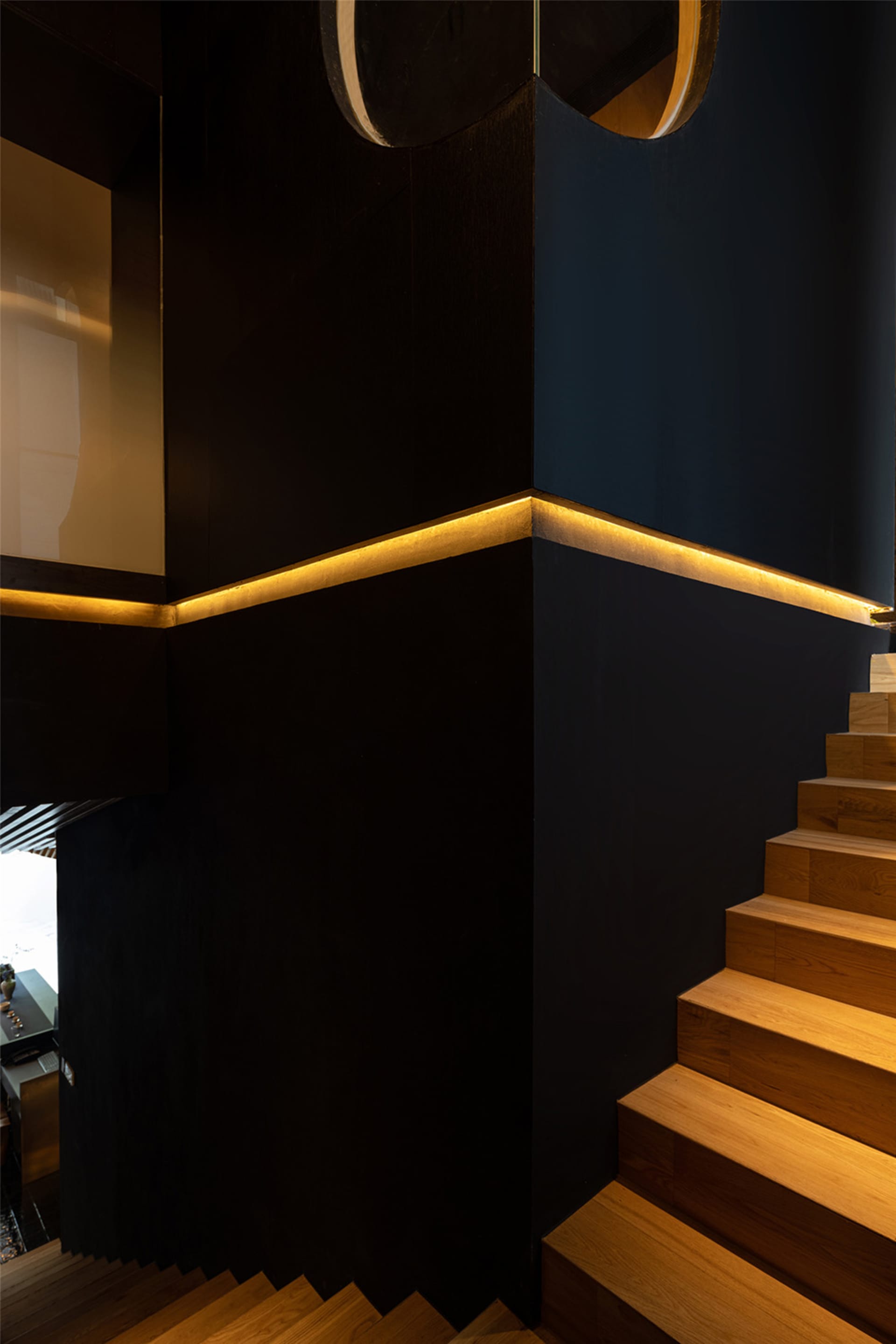 A black staircase with a wooden railing leads to another level of a building