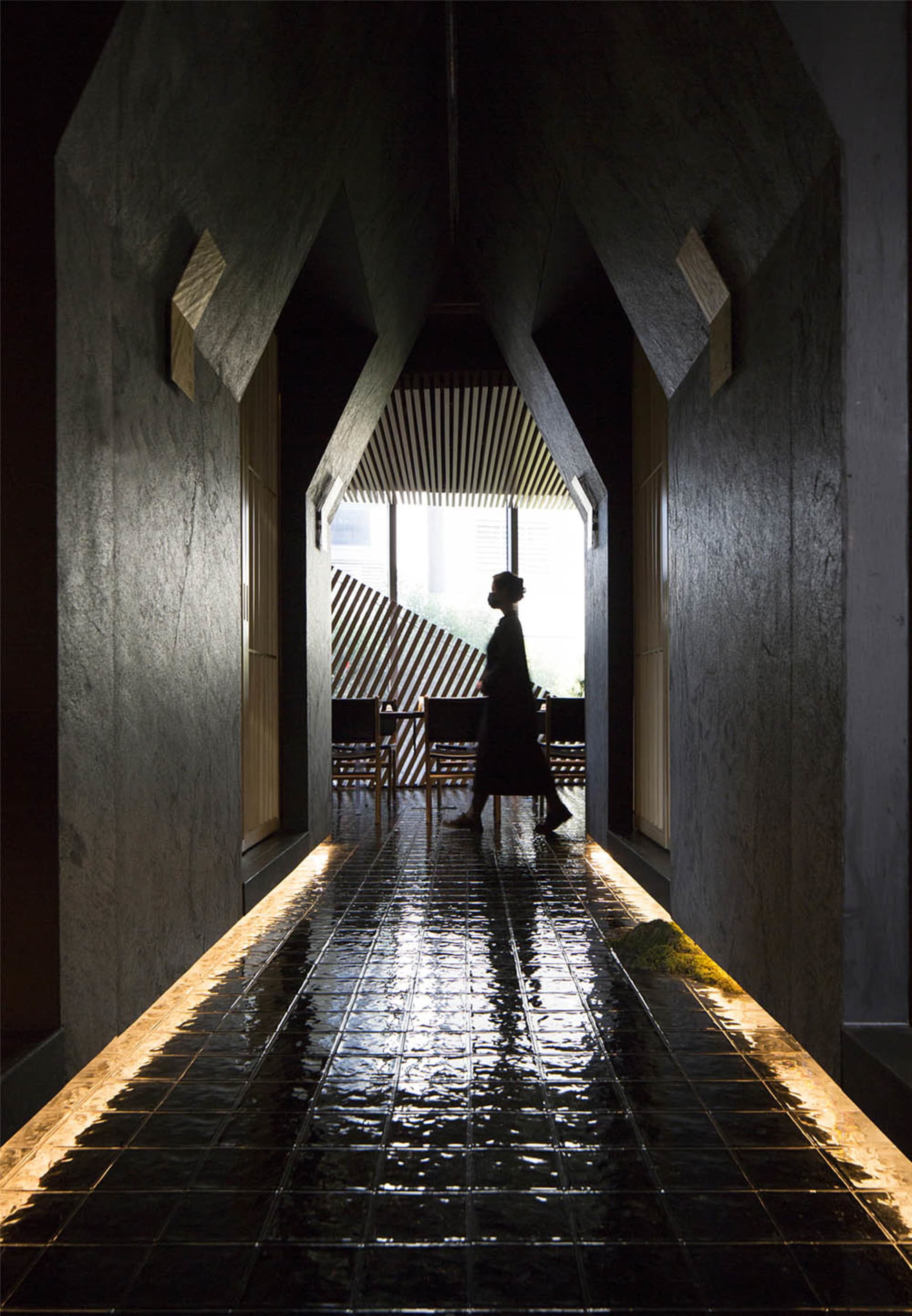 A calm and inviting hallway with a tiled floor, chairs, and a woman walking down the hall