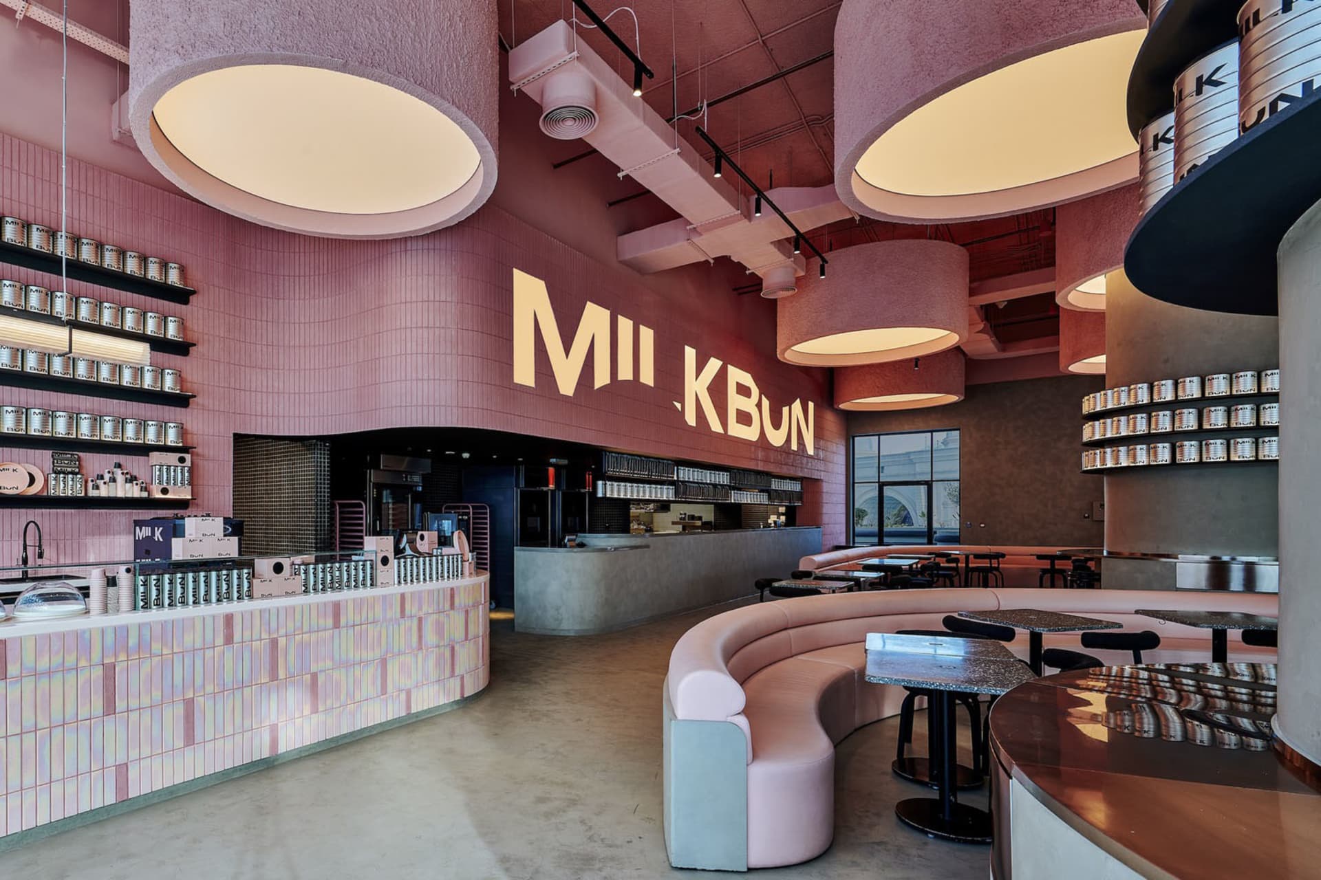 A modern restaurant interior with pink walls and ceiling, featuring dining tables and chairs in a comfortable and inviting atmosphere