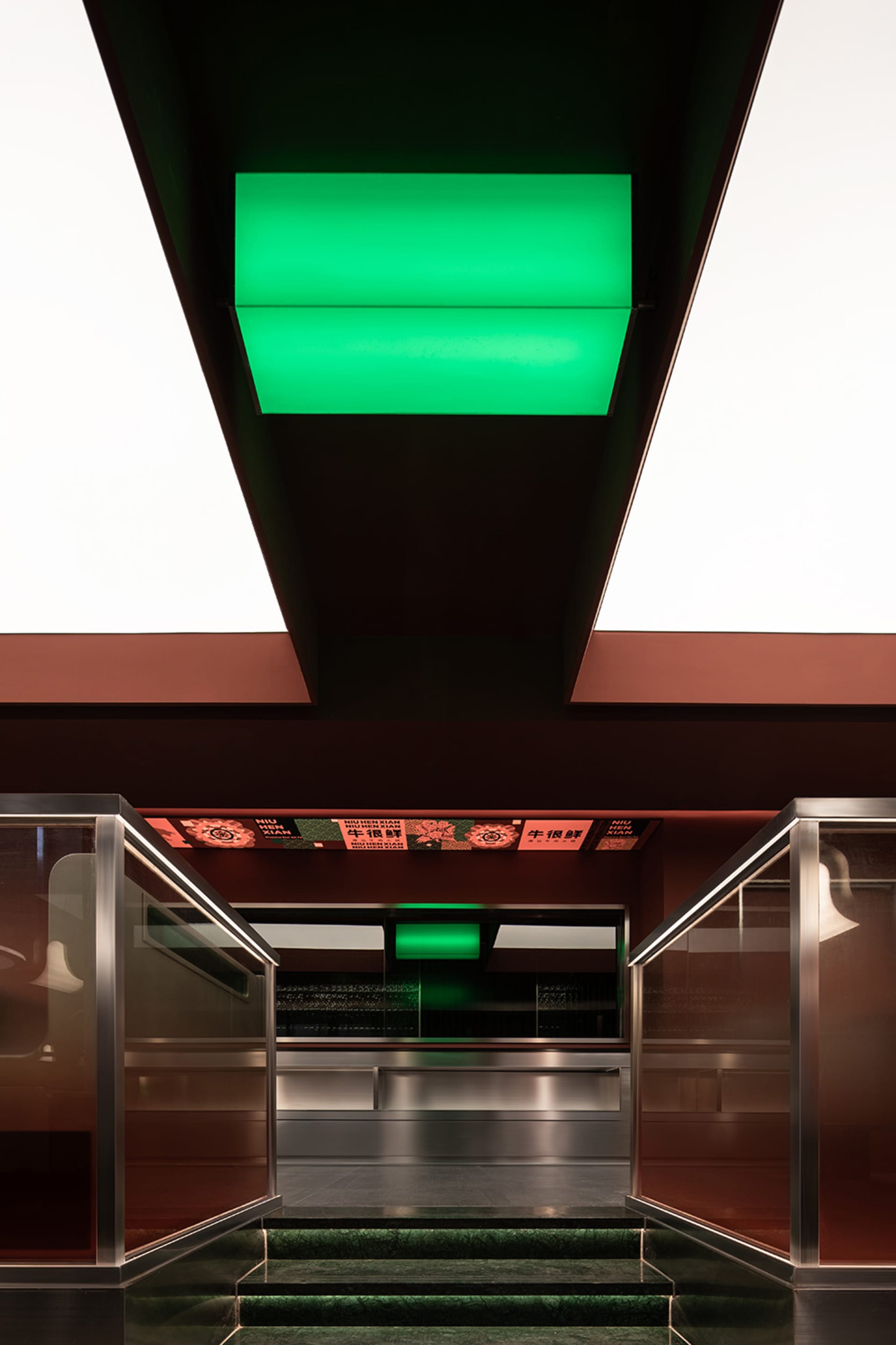 Industrial kitchen with green neon lights, two ovens, and three sinks, creating a modern and inviting cooking space