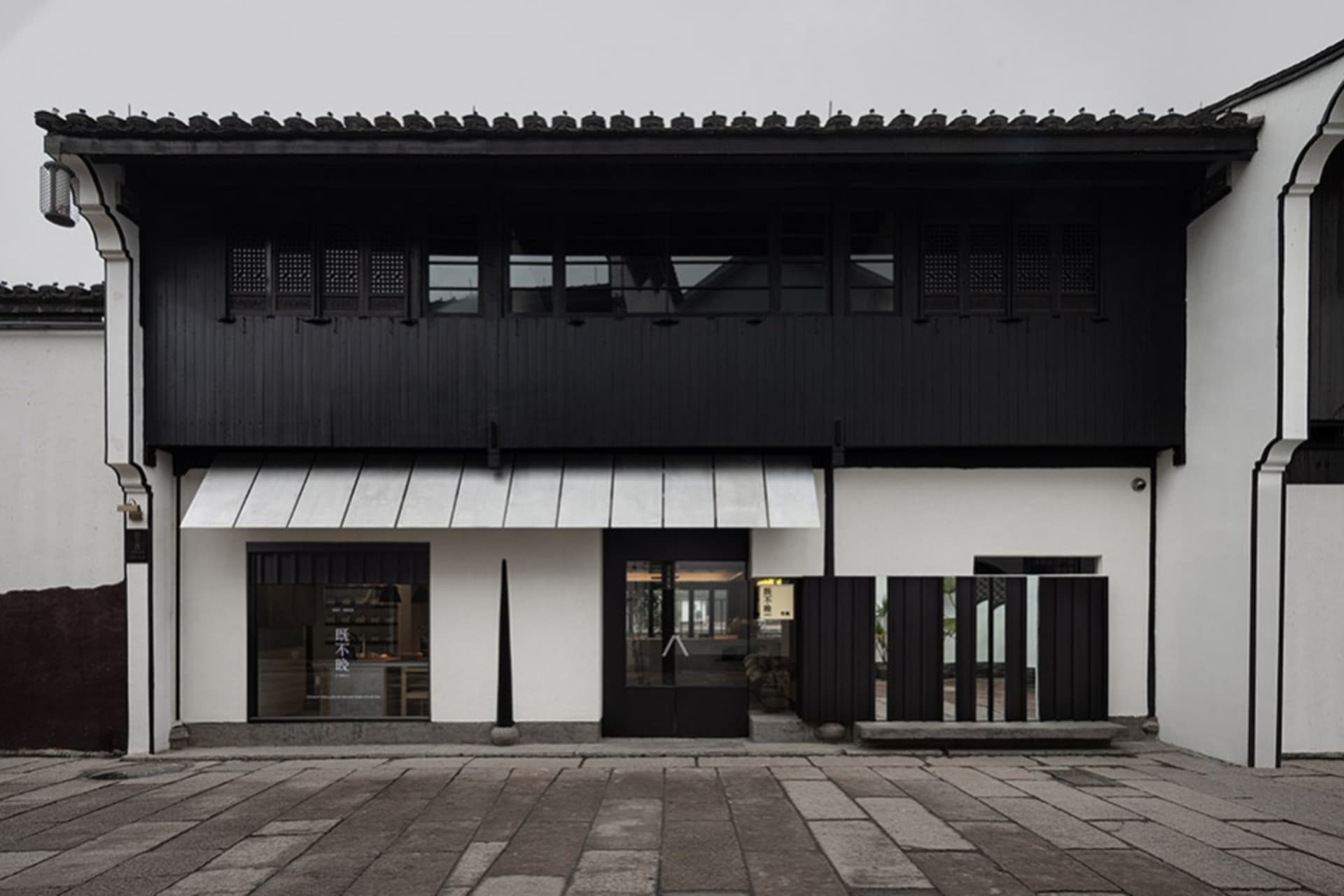 Old building with a black exterior, white roof, and large window, featuring a glass door and traditional architectural style