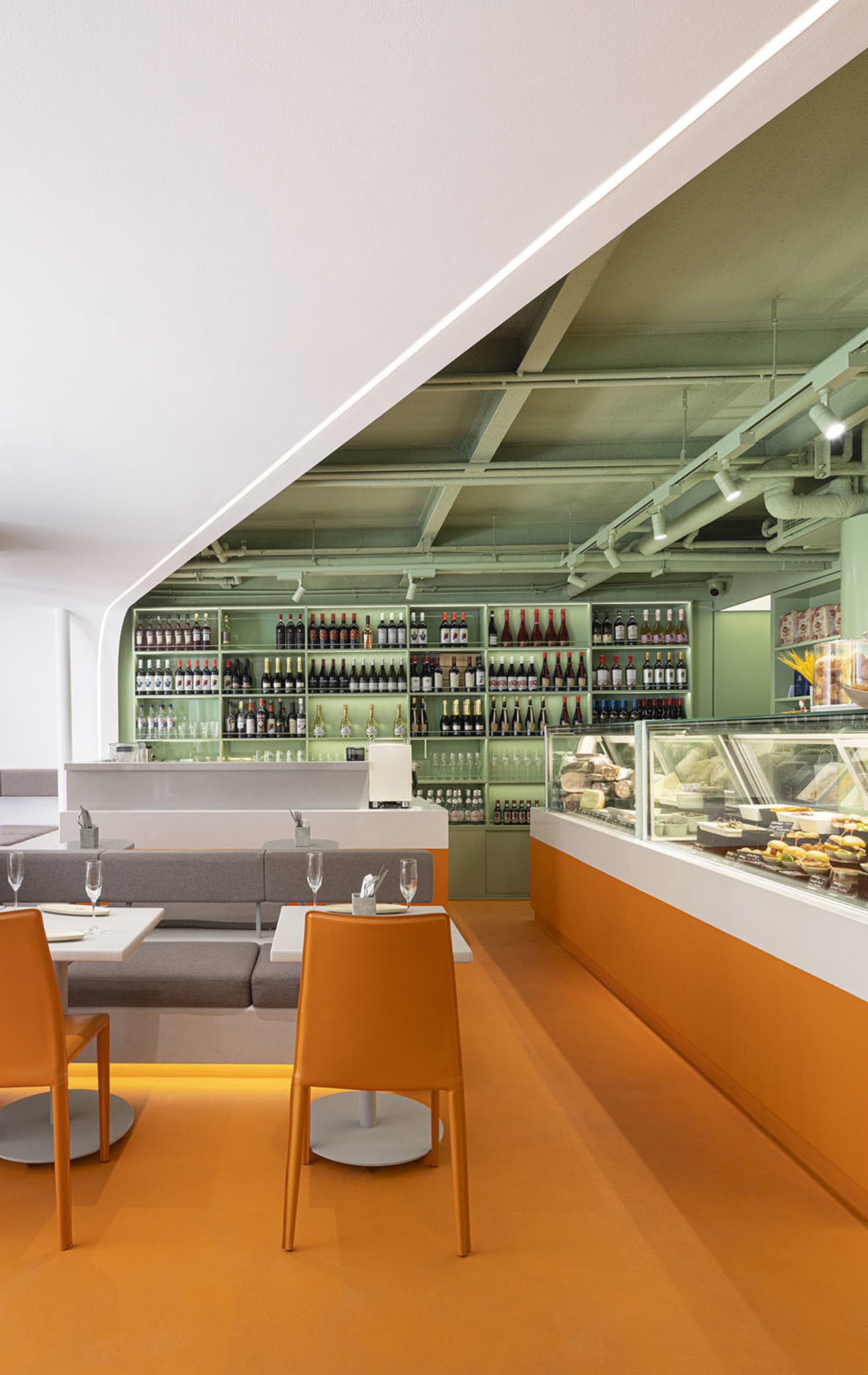 Warm and inviting restaurant interior with orange and white colors, multiple tables, chairs, and wine bottles