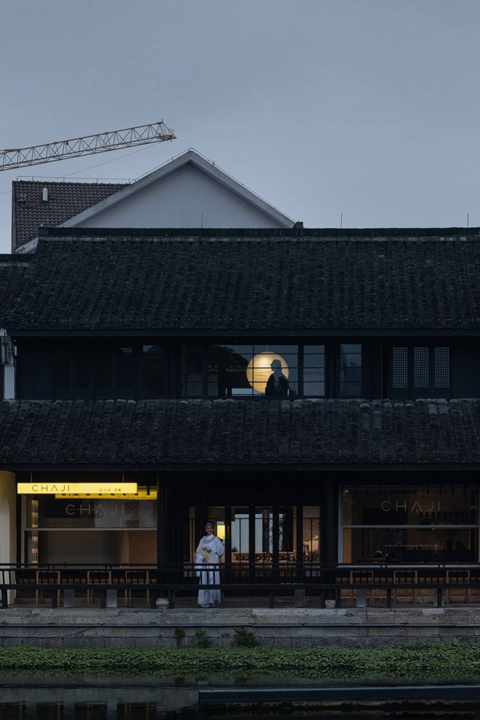 A photo of a building with a person standing in front, surrounded by city street elements and two chairs
