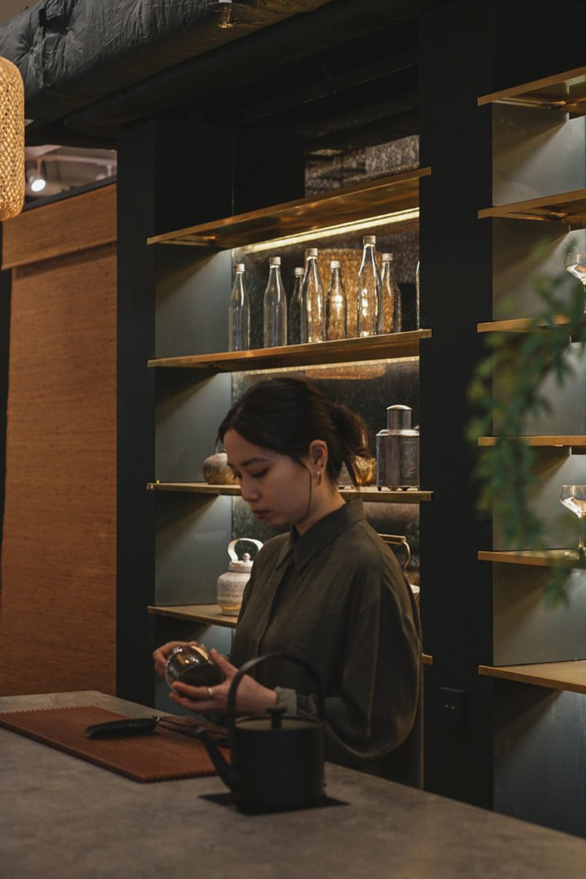 A woman stands in front of a display case filled with bottles in a modern retail space with a stylish atmosphere