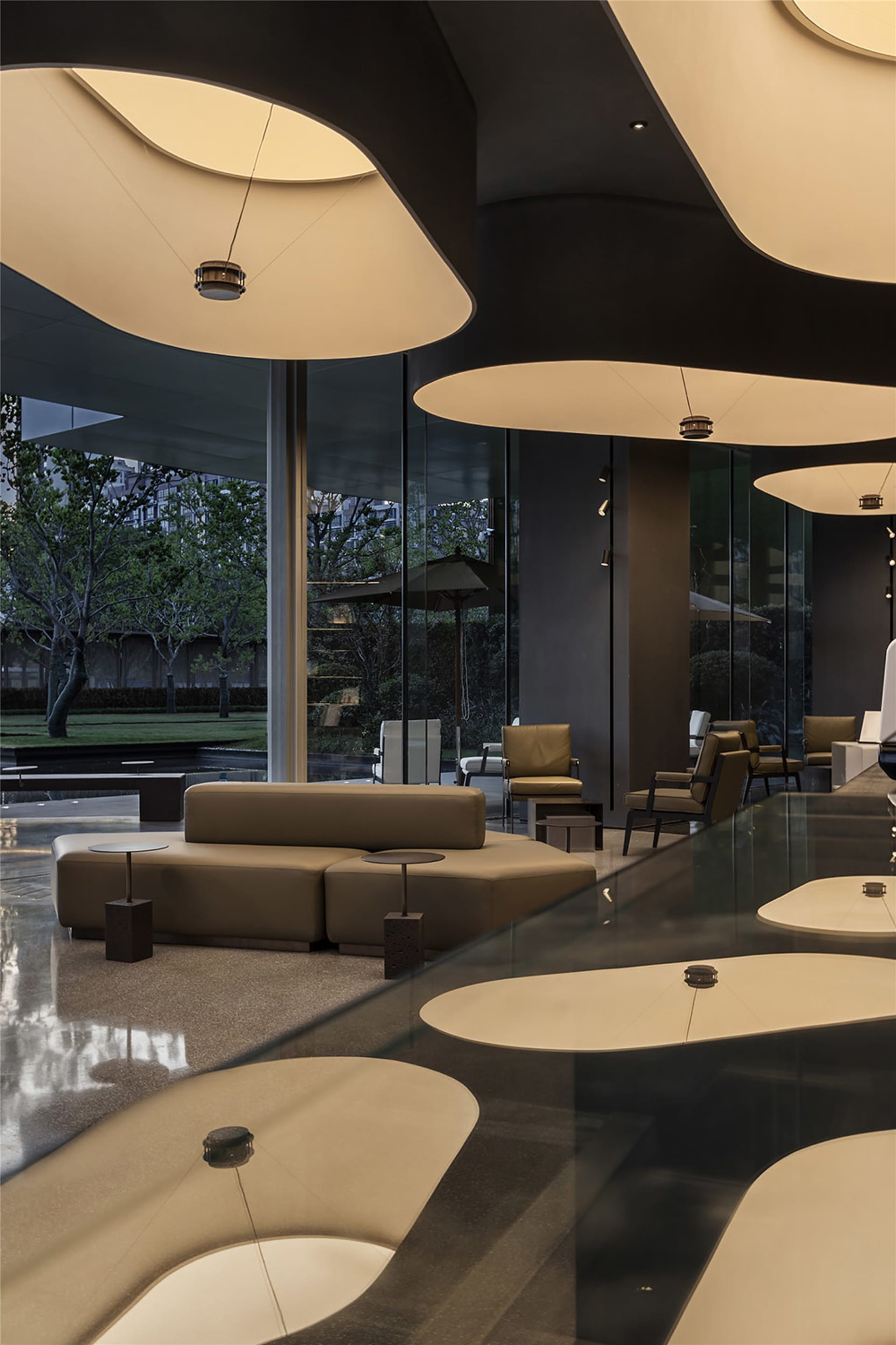 A modern cafe with a large glass table surrounded by chairs and couches, featuring a combination of wood and glass elements, warm lighting, and a contemporary feel