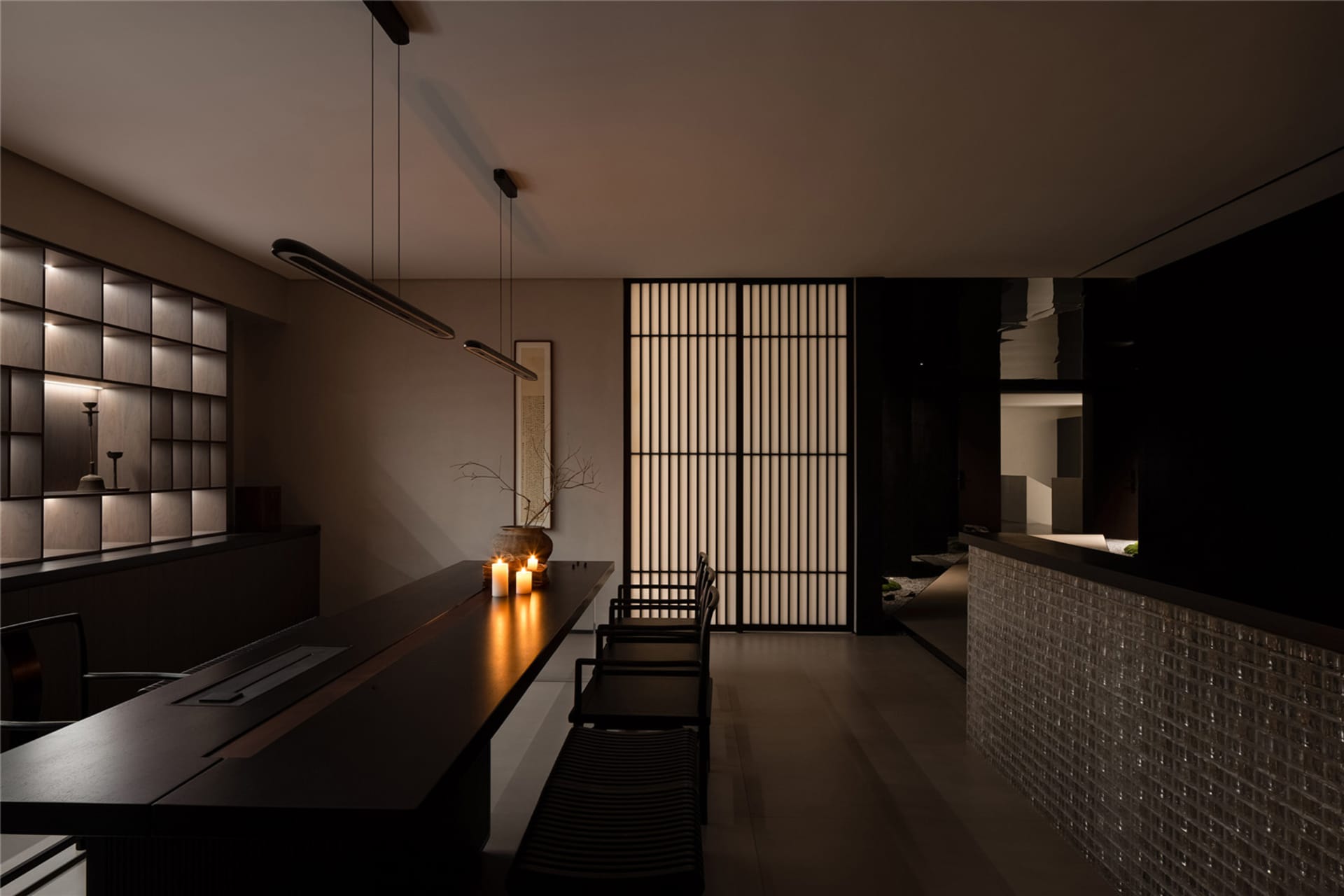 Modern kitchen and dining space with a black countertop, two chairs, a potted plant, and a vase, creating a comfortable and stylish atmosphere