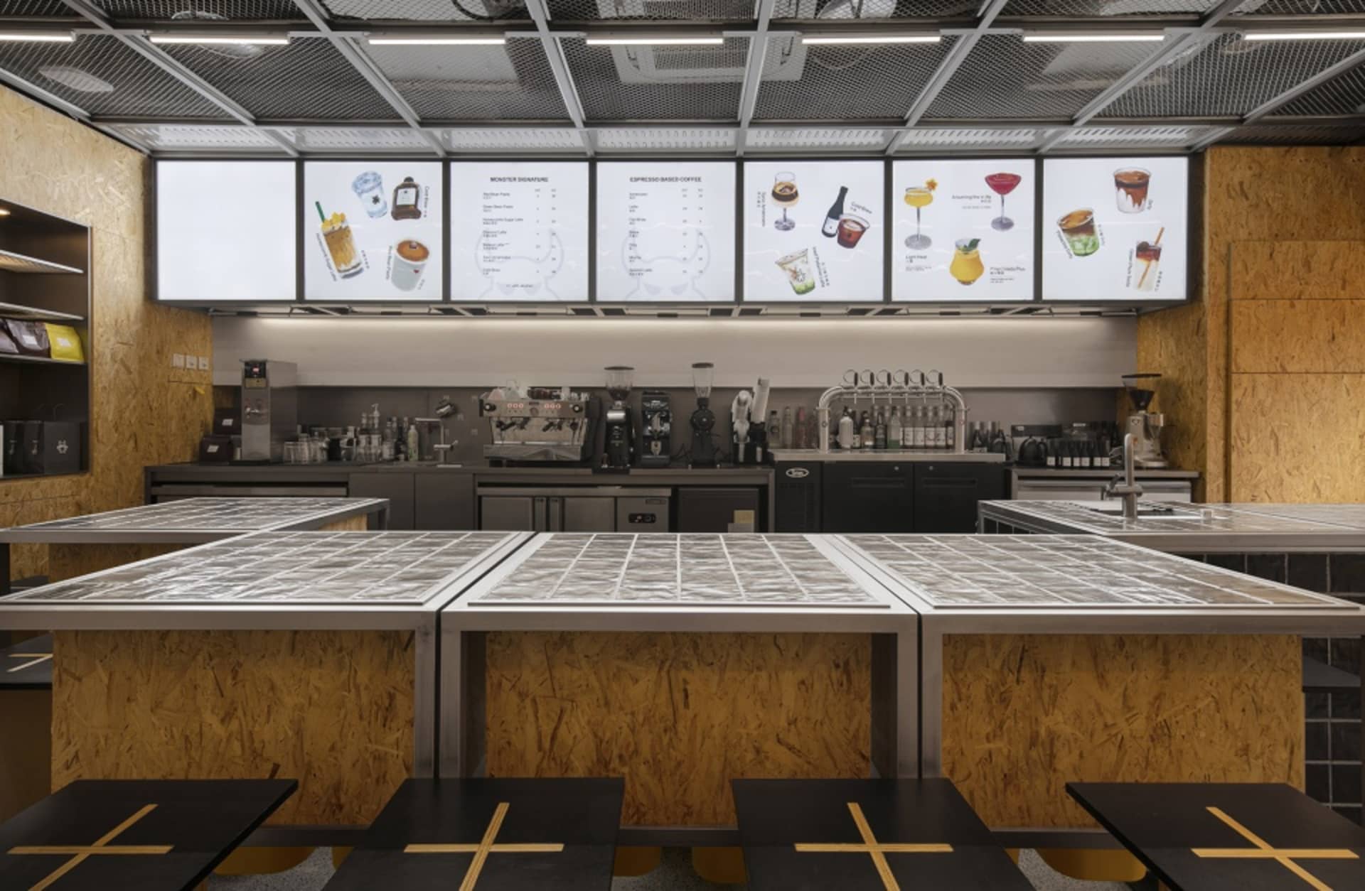 Industrial kitchen with multiple tables, chairs, and appliances, featuring functional and organized spaces for food preparation and serving