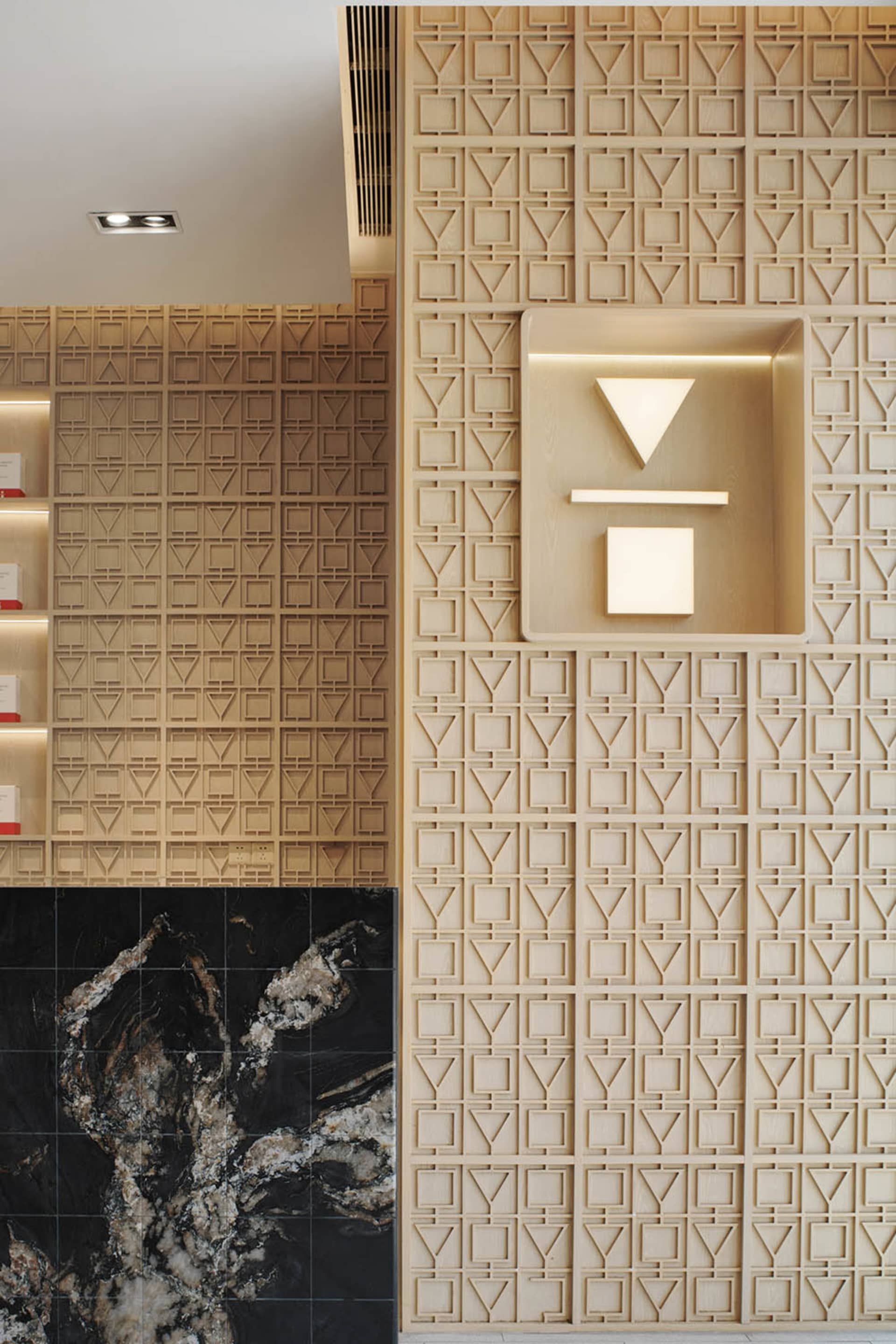 A modern interior space with a wall covered in a wood triangle pattern, featuring two wall lights and a stylish atmosphere