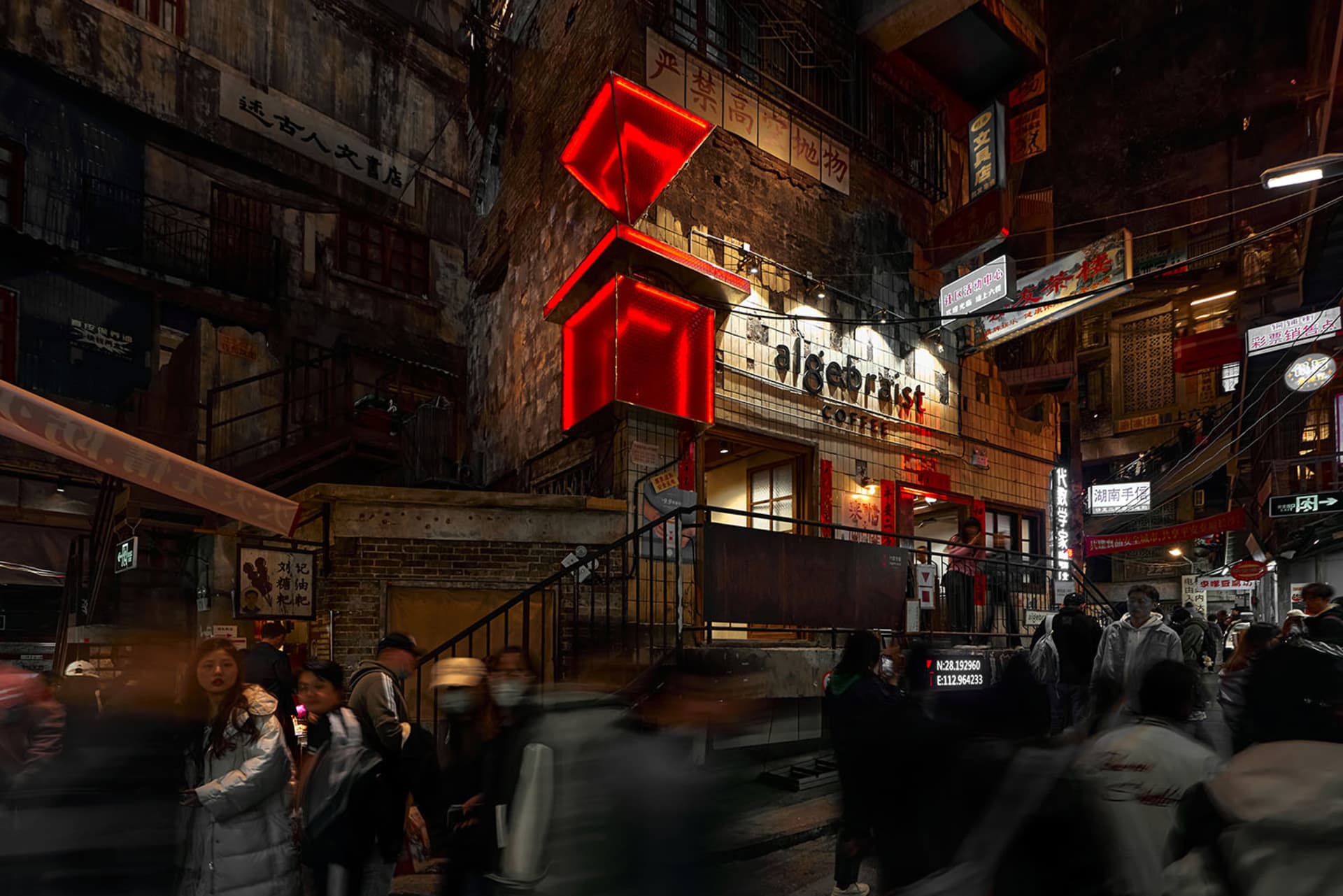 A bustling city street scene at night with a coffee shop lit up and people walking around